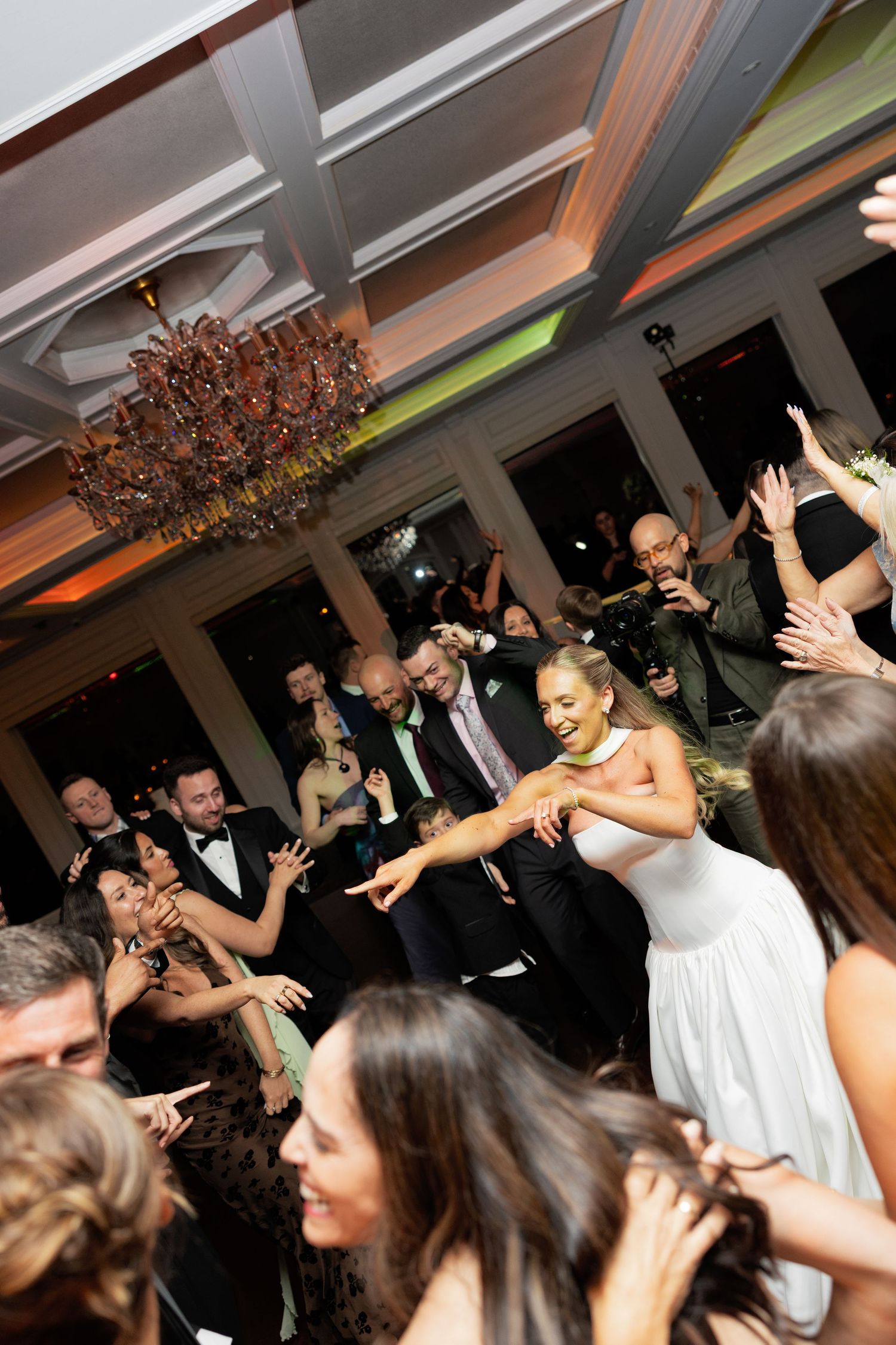 Bride dancing joyfully with guests at lively wedding reception.