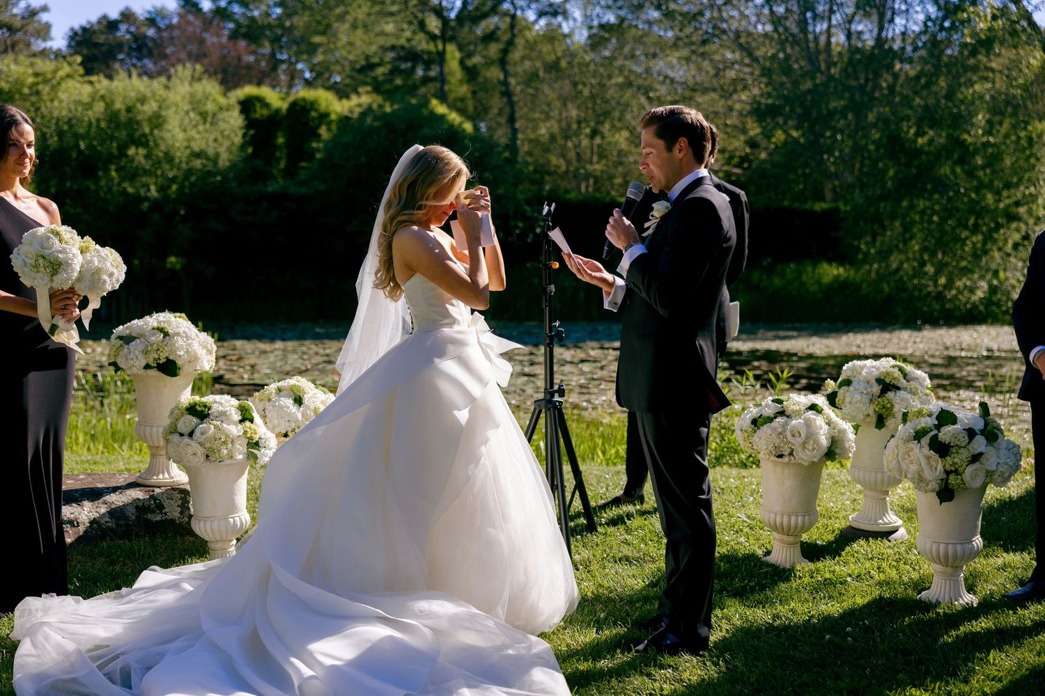 Wedding party poses for photos in a sunny outdoor garden setting.