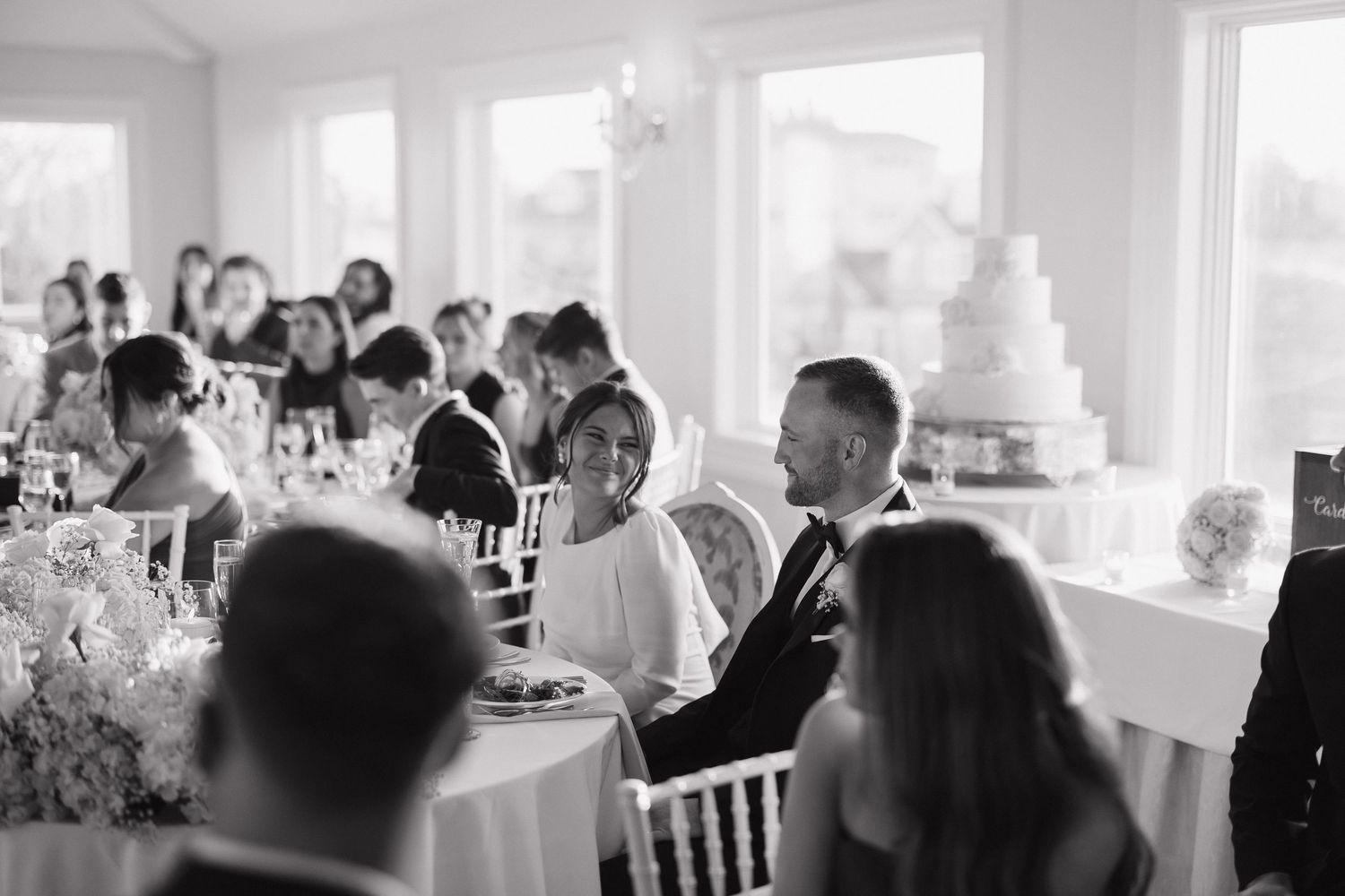 Bright sunlit reception venue with large windows and tables set for a wedding celebration.