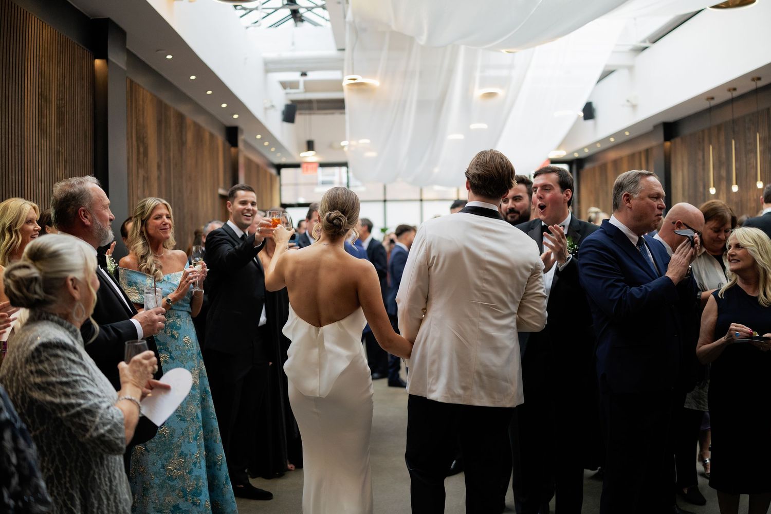 Couples dance together at an elegant indoor reception venue with white draped ceilings and warm lighting.