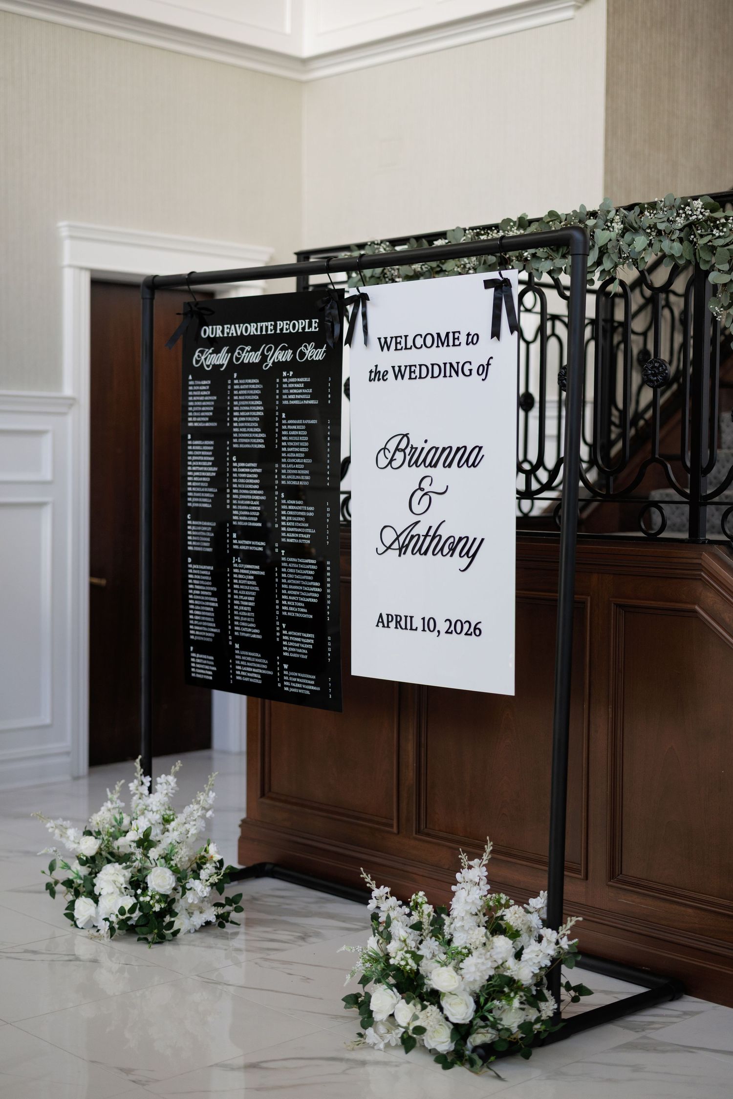 Elegant wedding welcome sign for Brianna and Anthony, April 10, 2026, with seating chart and white floral arrangements.