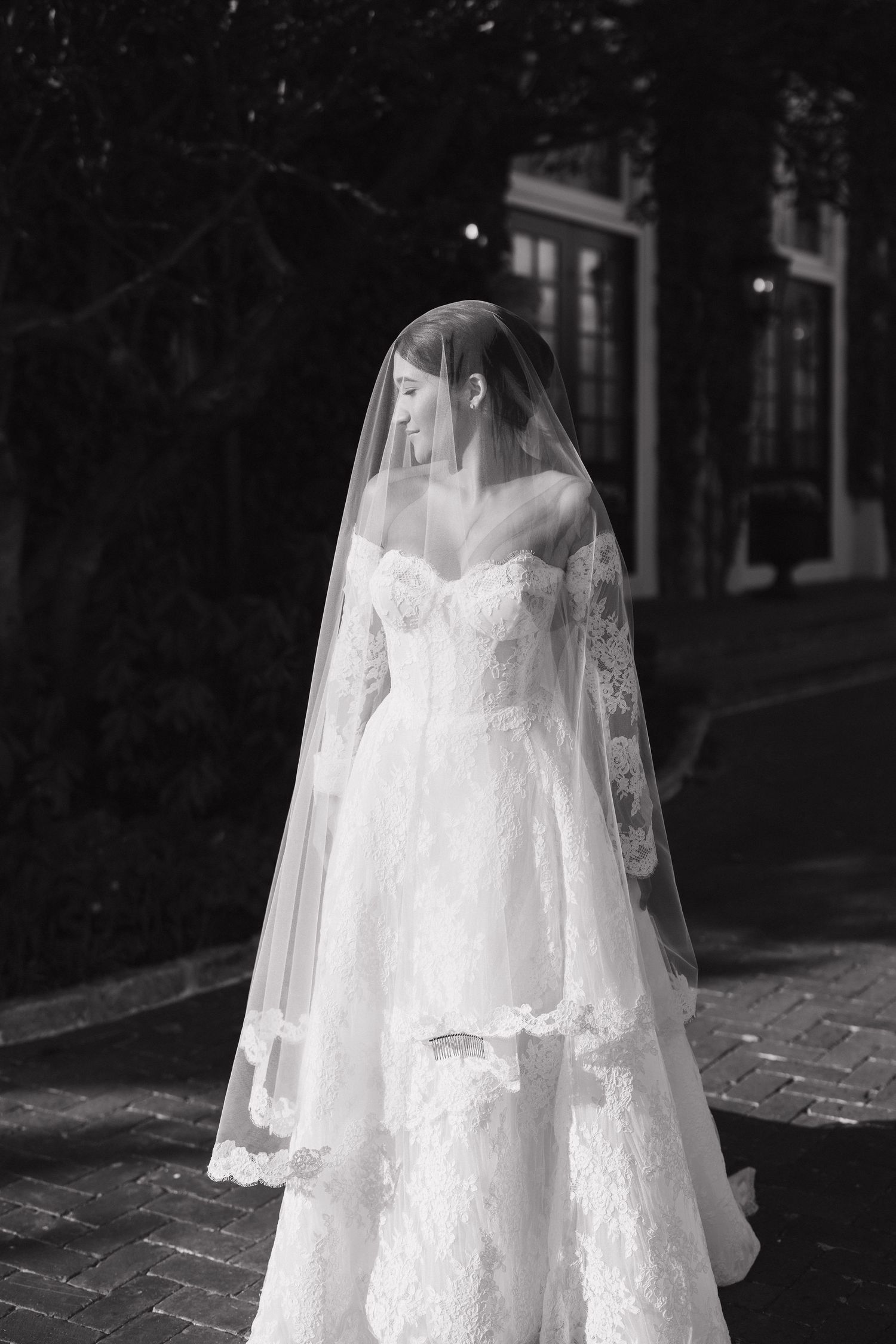 A romantic bridal portrait series in black and white showing flowing white lace wedding dress and veil details.