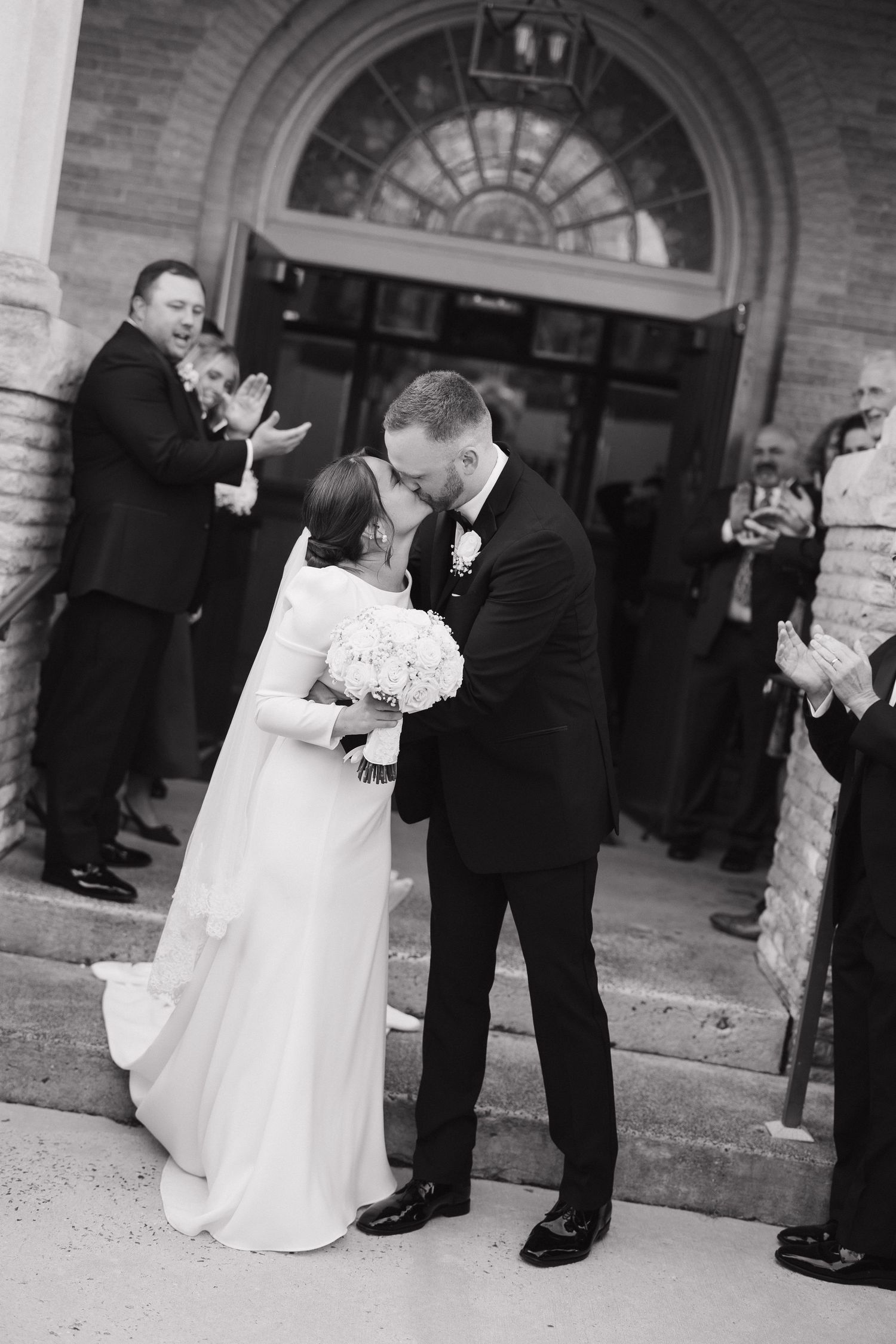 Black and white sequence of wedding couple sharing a romantic dance moment outside a brick building entrance.