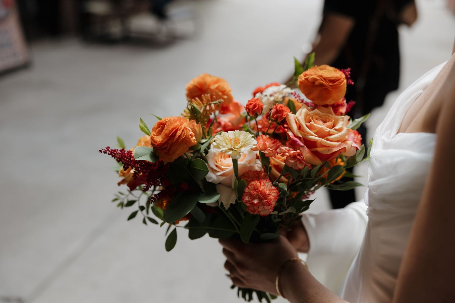 Vibrant coral and peach wedding bouquet with garden roses and greenery.
