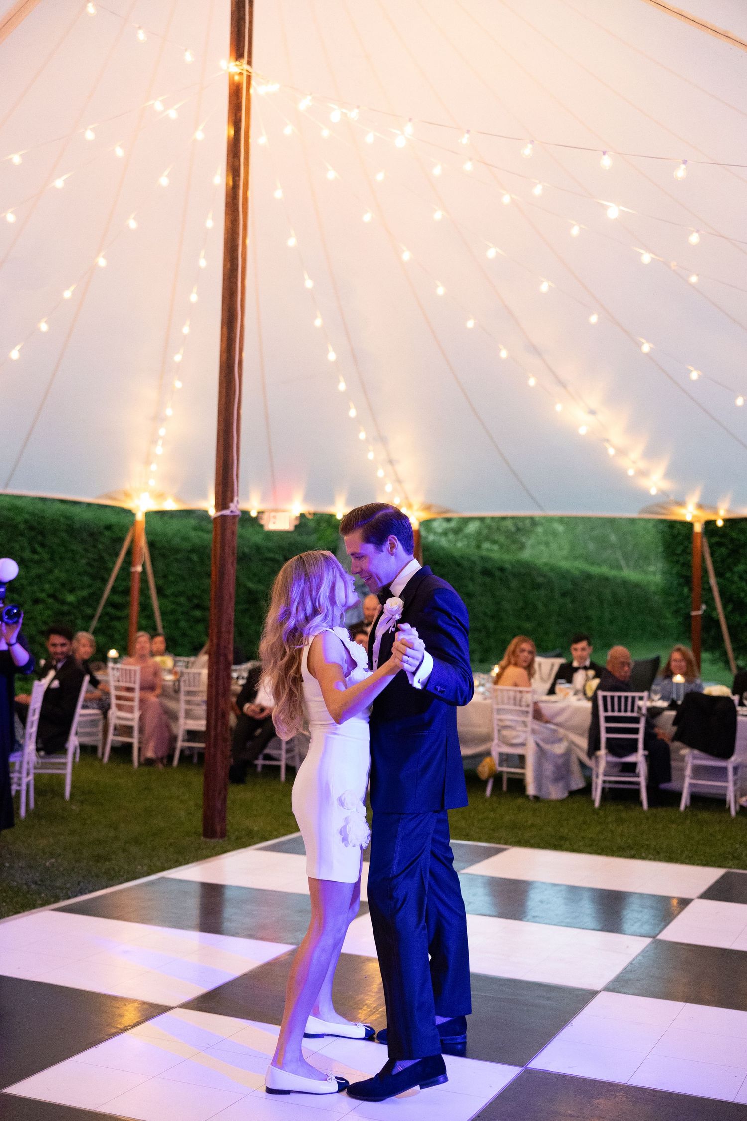 First dance sequence under twinkling lights and tent with black and white checkered dance floor.