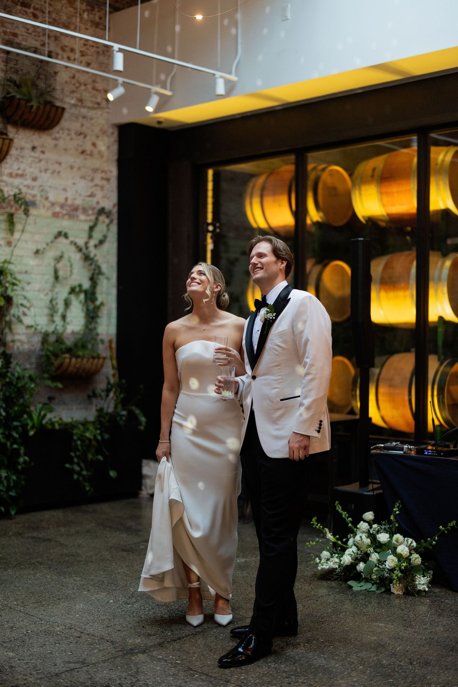 A couple shares a joyful moment together during their wedding celebration in a rustic brick-walled venue.