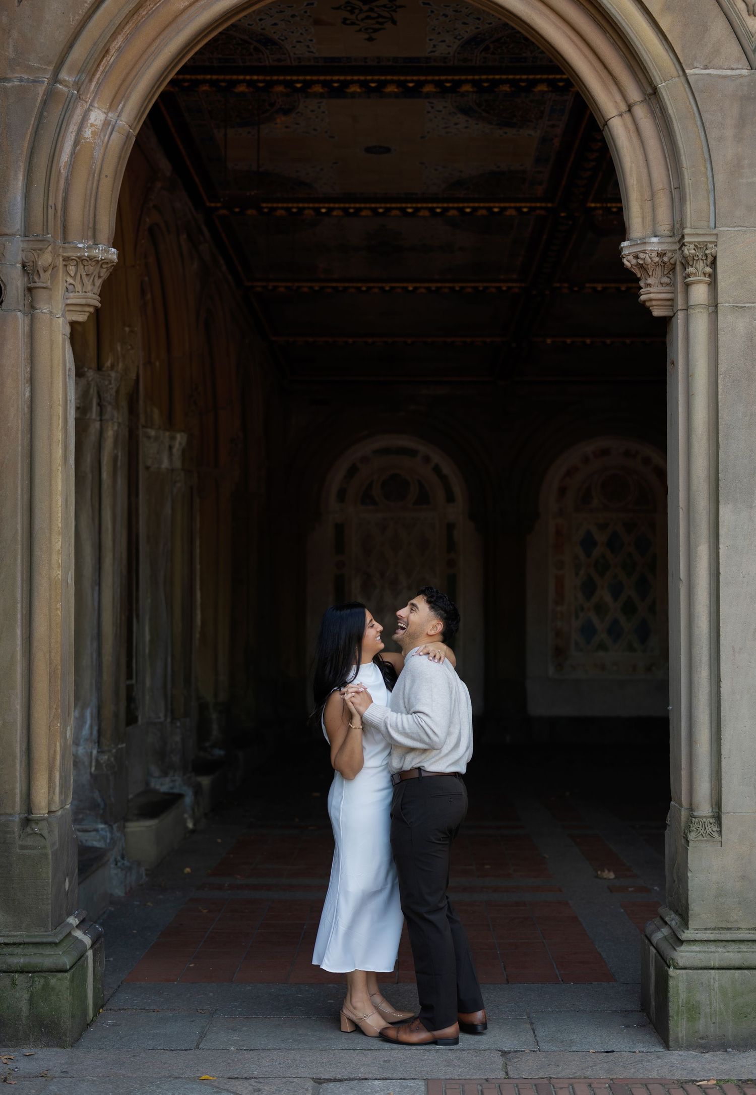 Couple sharing tender moments under a historic stone archway.
