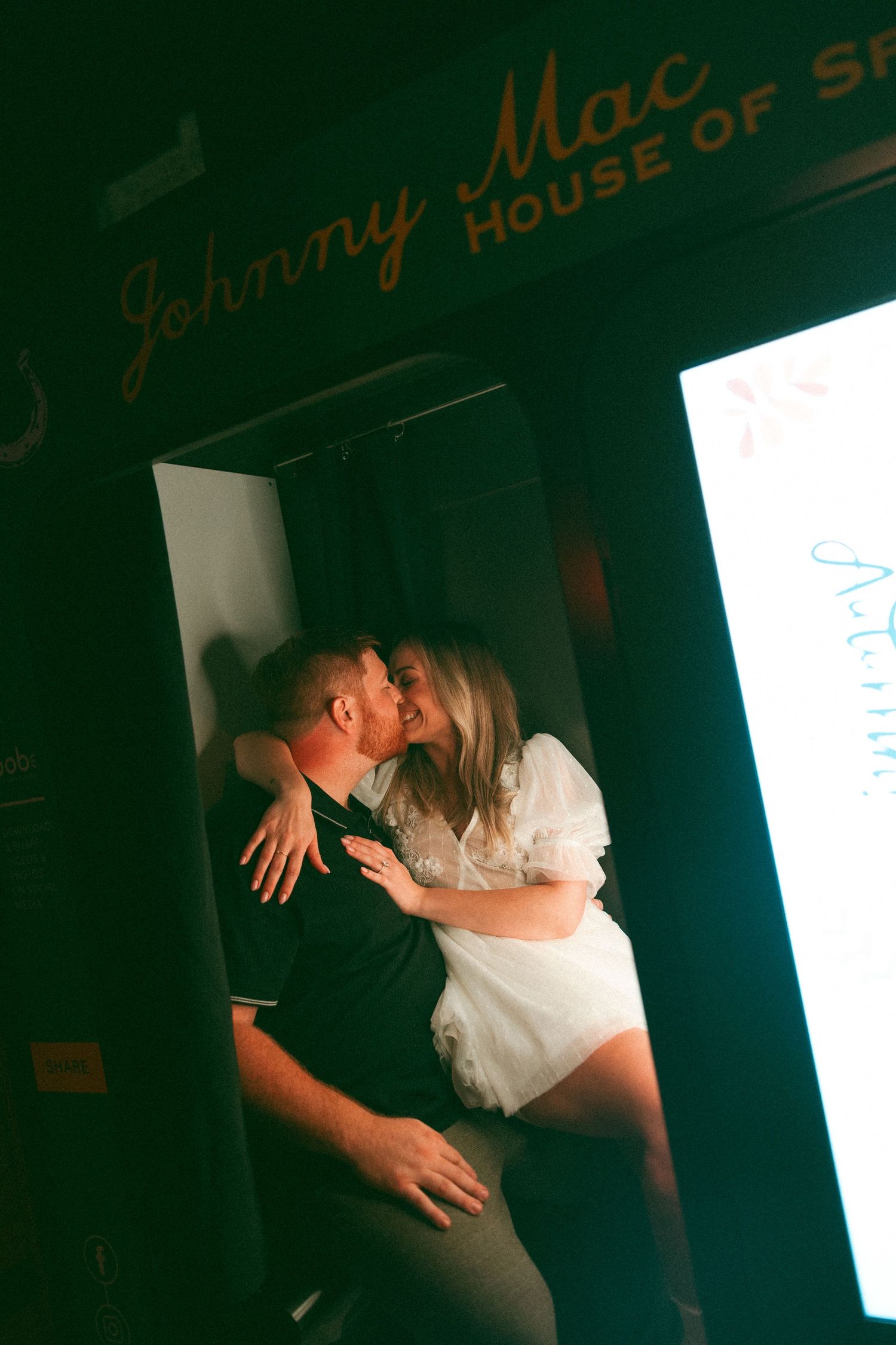 Couple shares intimate dance moment in dimly lit venue with neon signage glowing in background.