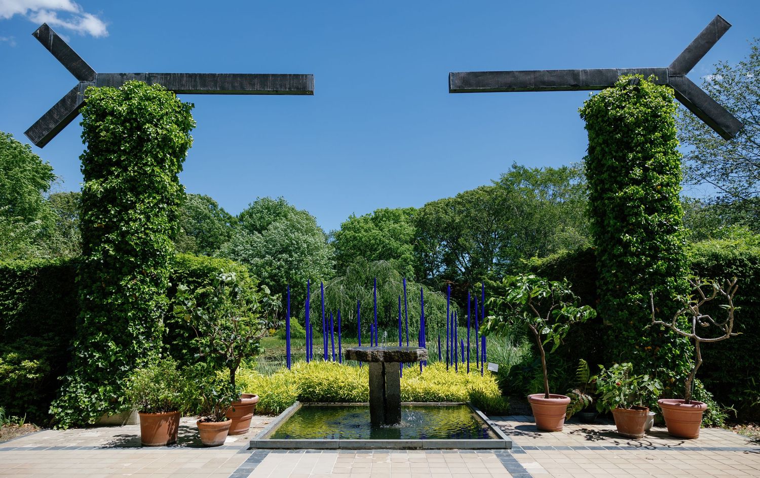 Elegant outdoor wedding venue with white tents and lush green landscaping on a sunny summer day.