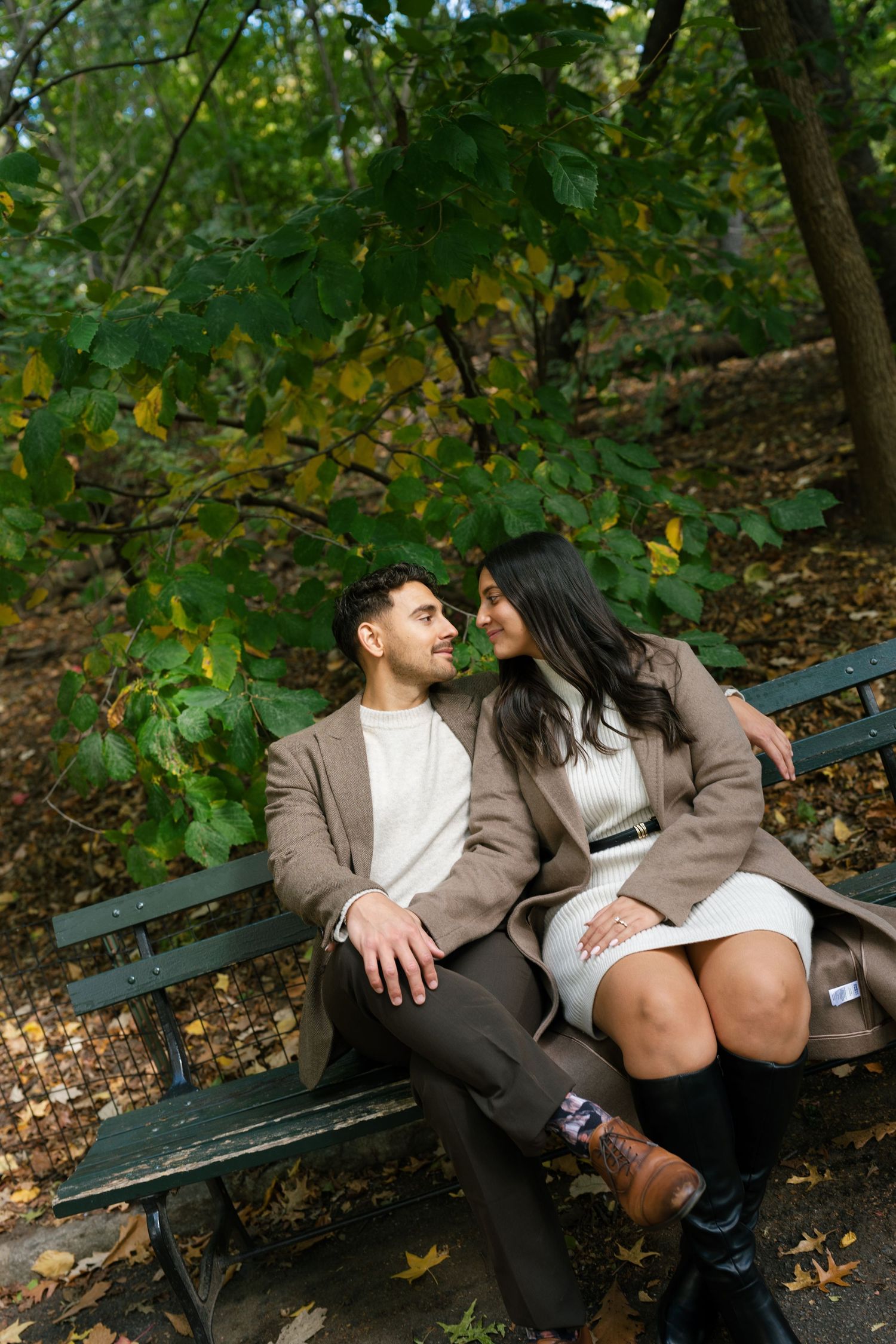 Couple relaxing on a park bench surrounded by fall foliage.