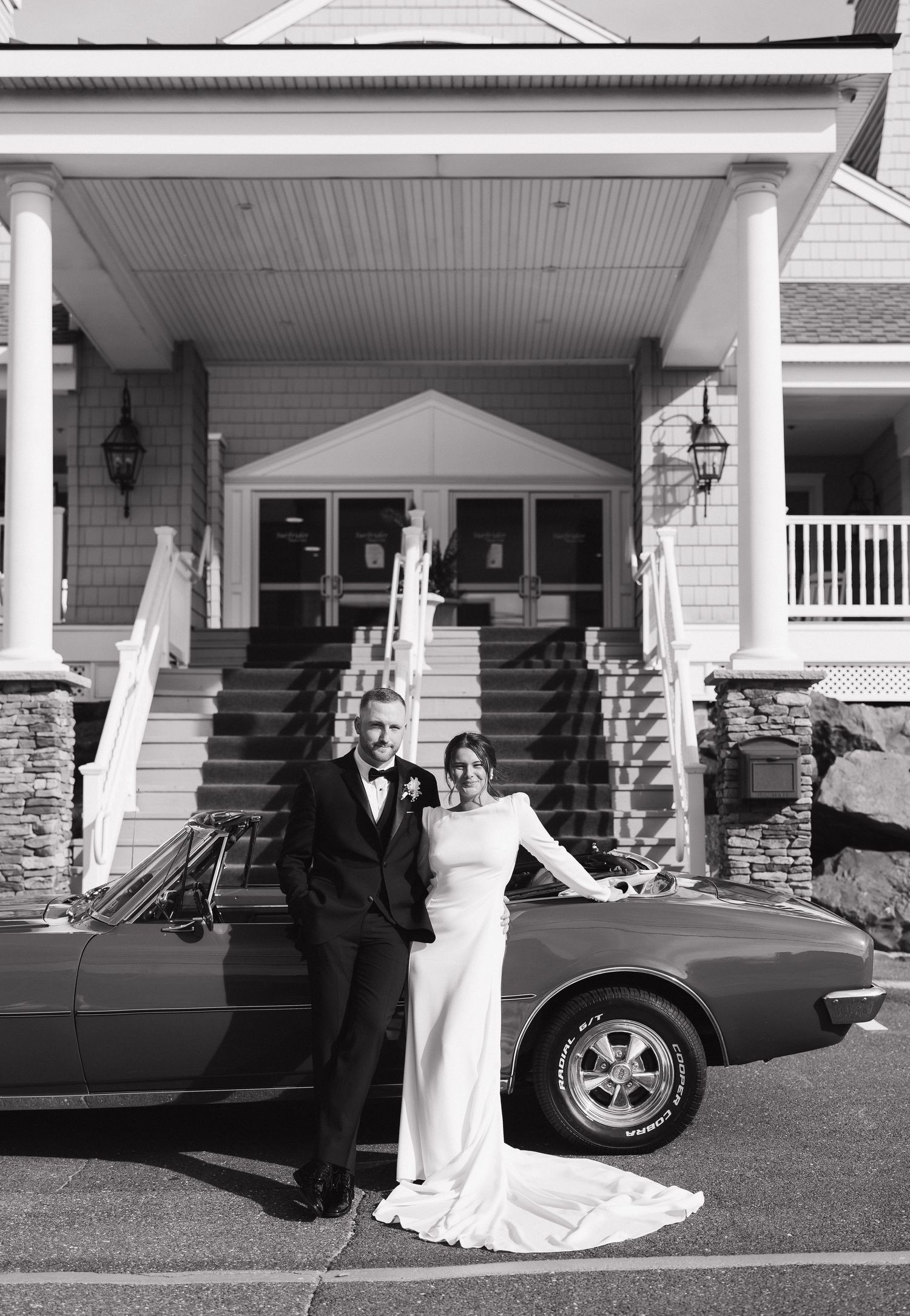 Black and white wedding photos showing couple posing by classic car outside vintage style house.