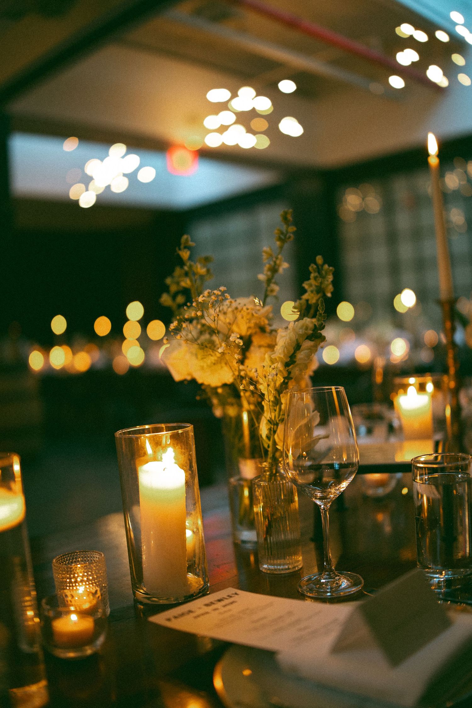 Romantic candlelit table settings with glowing votives and floral centerpieces create an intimate evening ambiance.