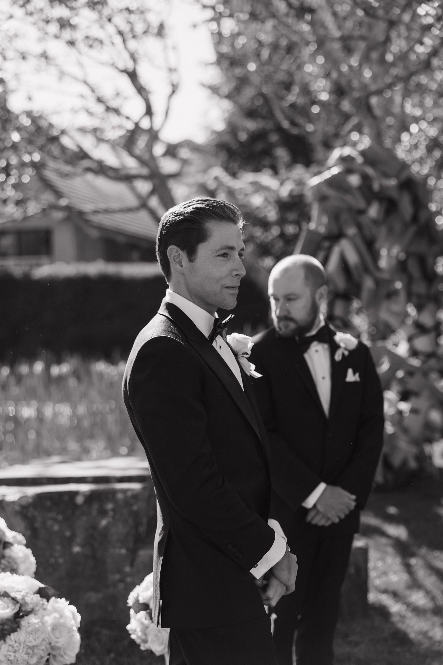 Groomsmen in black tuxedos share an emotional moment before the wedding ceremony.