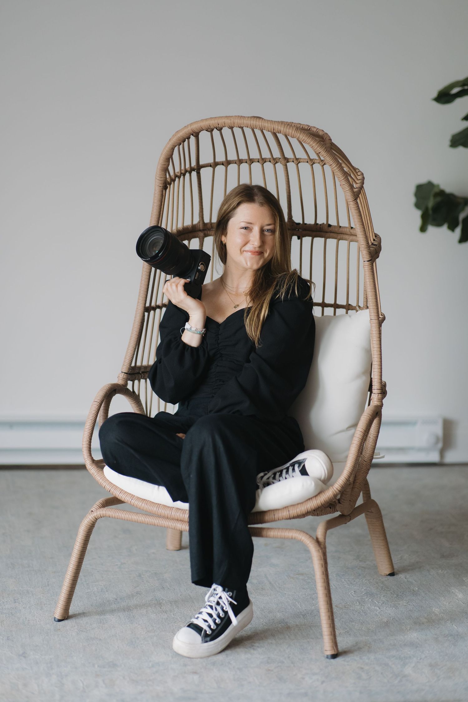 A photographer relaxing in a rattan chair while holding professional camera equipment.
