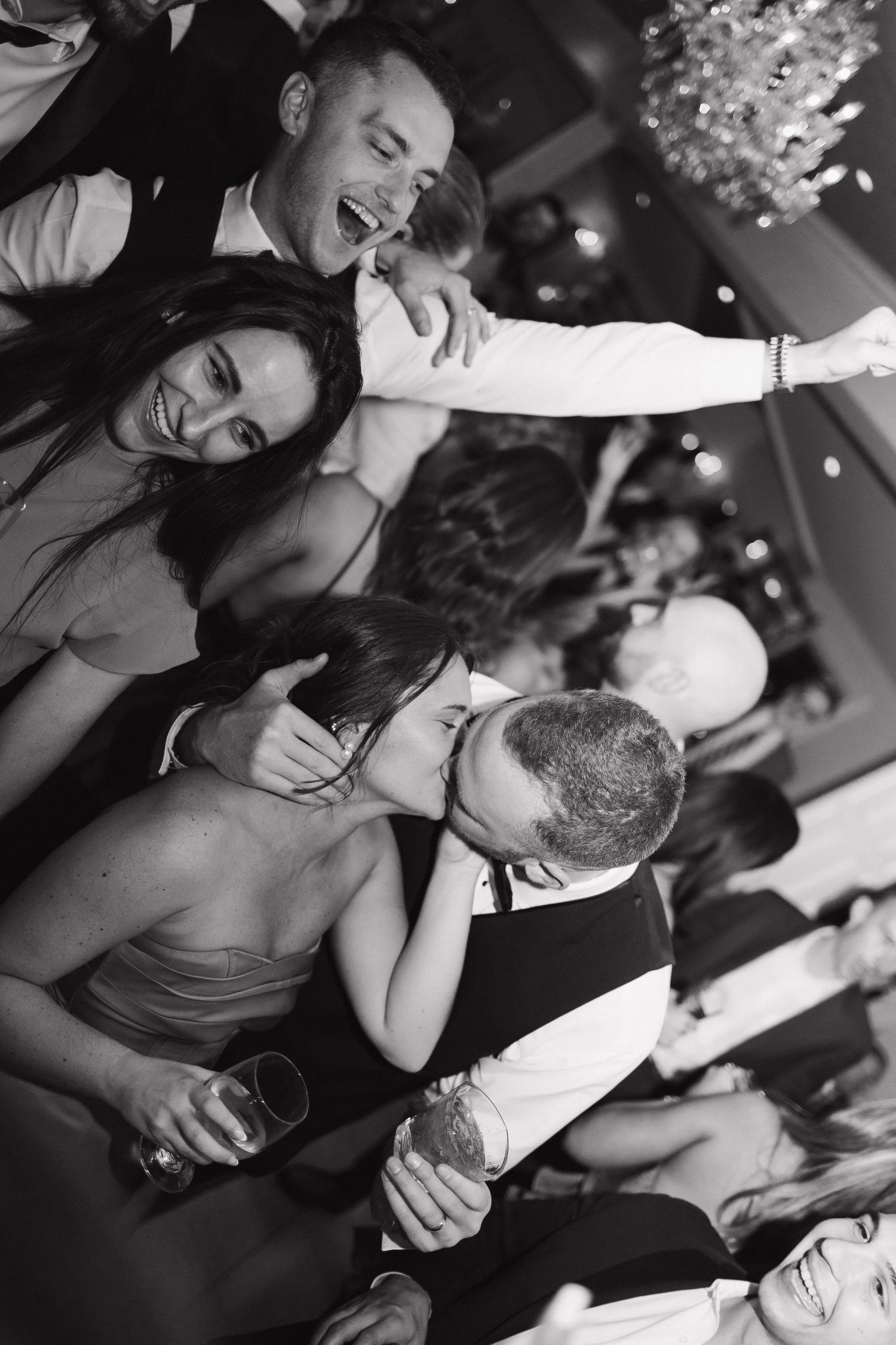 Black and white candid shots of wedding guests laughing and enjoying the dance floor celebration.