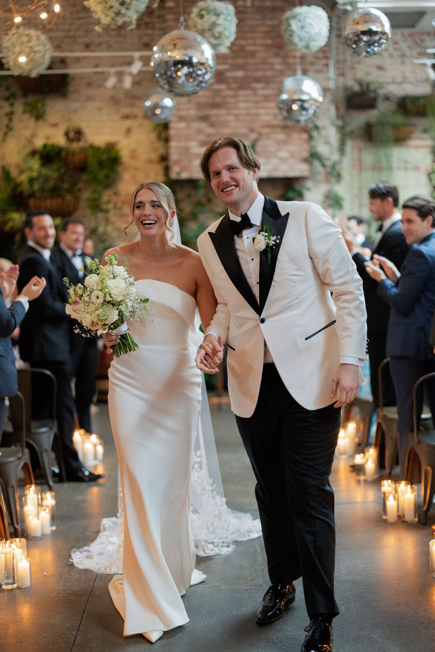 Newlyweds share a playful dance moment under twinkling lights and disco balls in an industrial venue.
