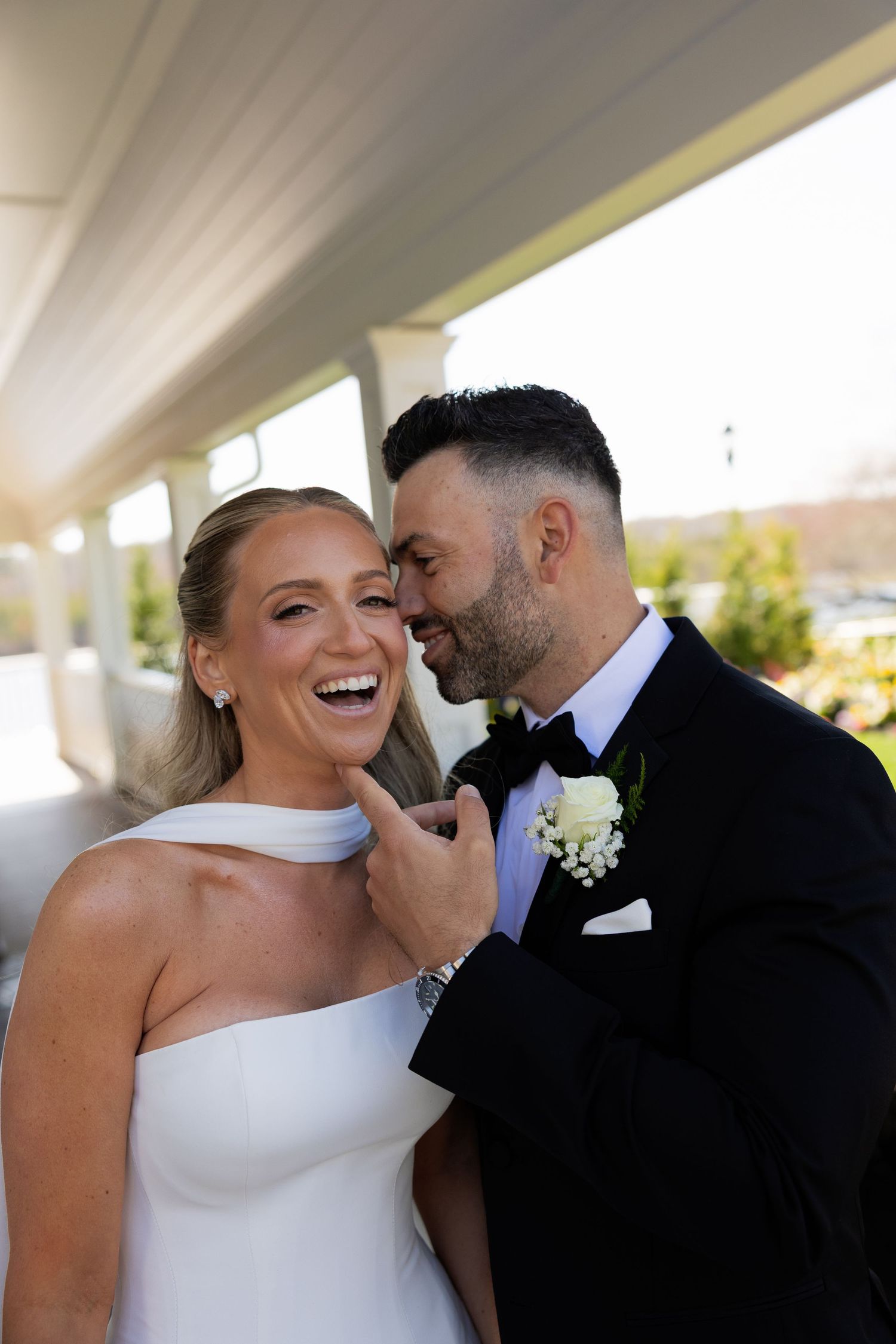 Laughing bride and groom sharing a joyful intimate moment during their wedding celebration.