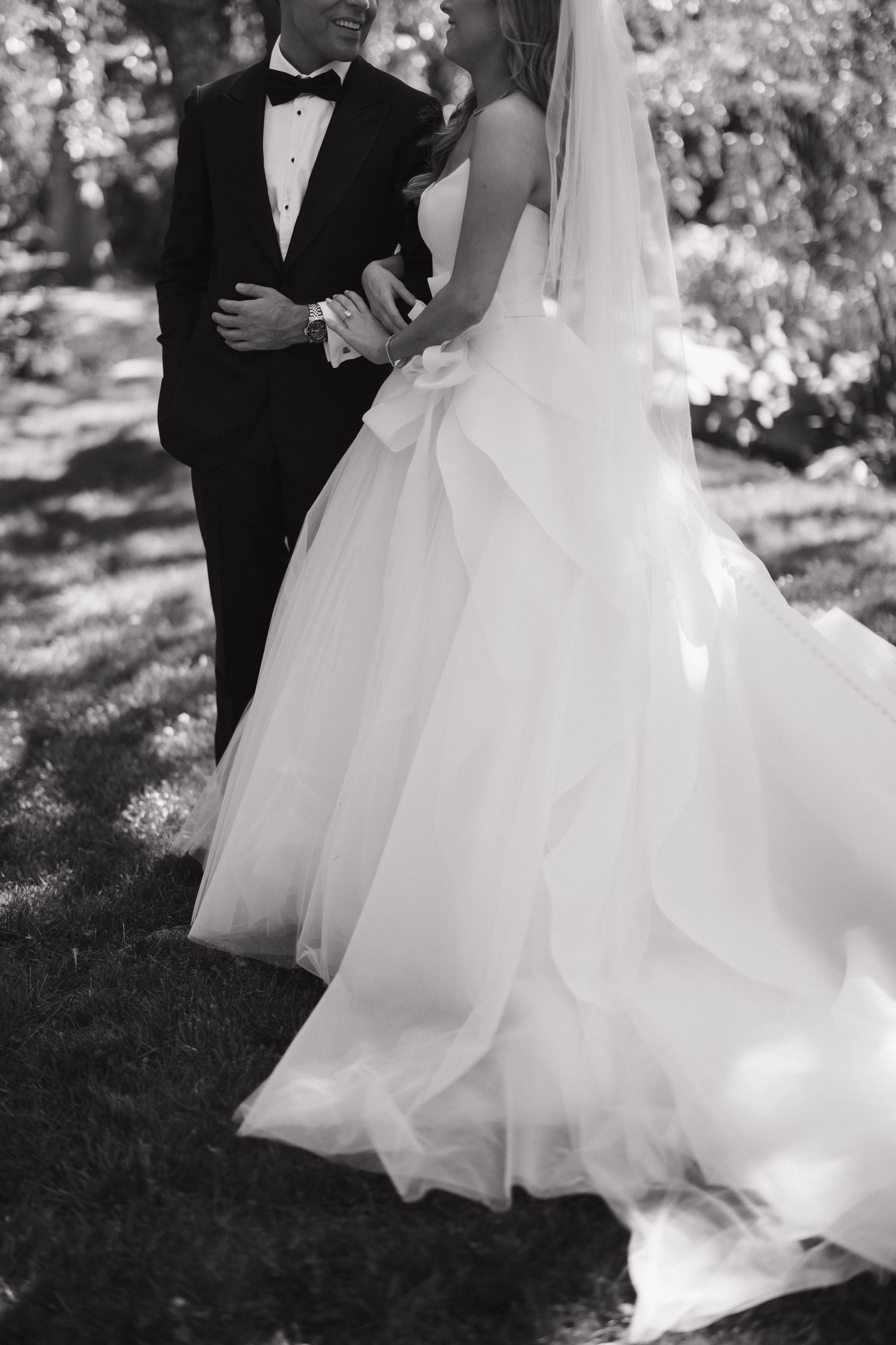Elegant black and white wedding photography capturing flowing dress movement in a natural setting.