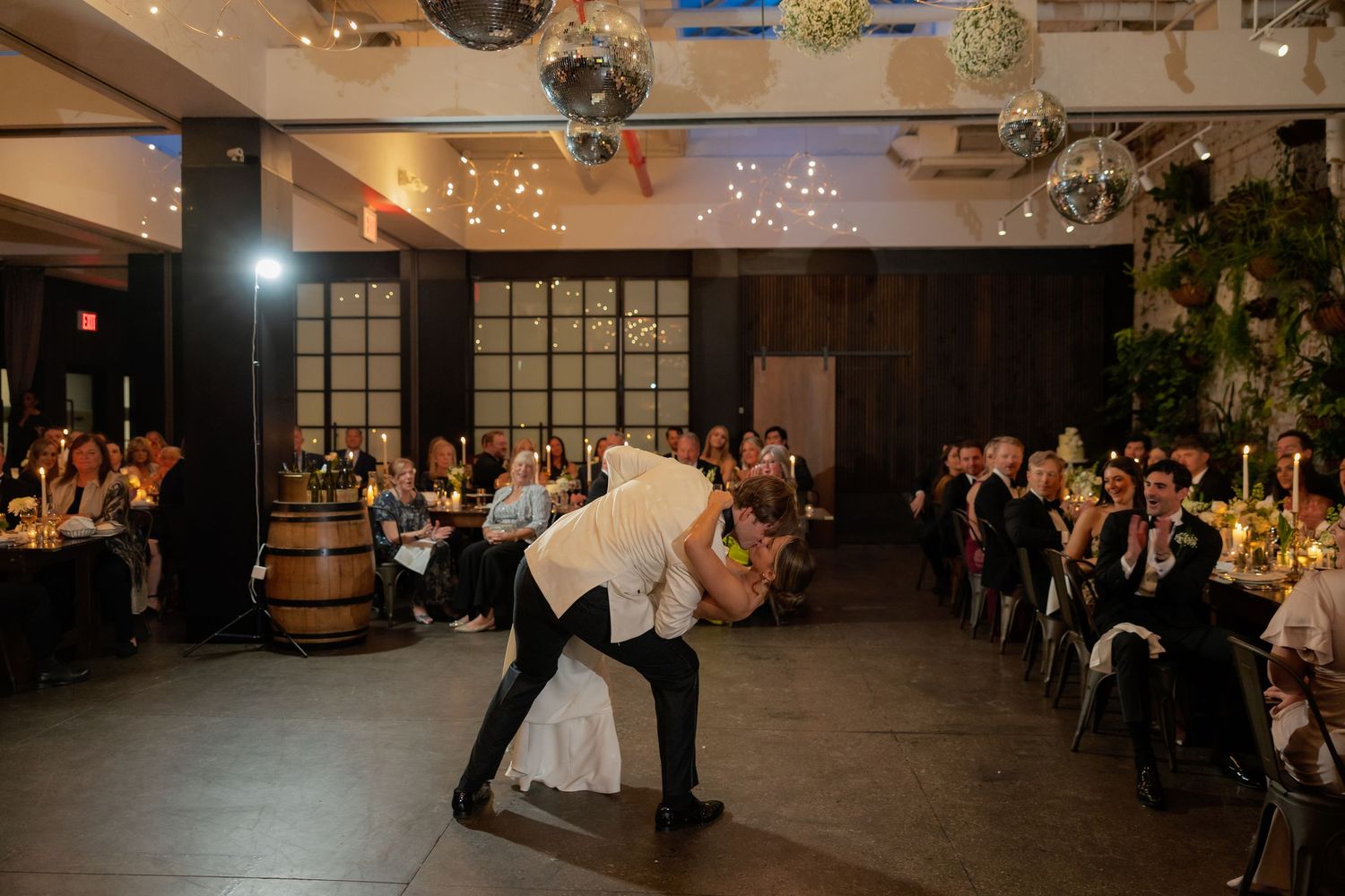 A couple shares their first dance at a wedding reception under twinkling lights and disco balls.