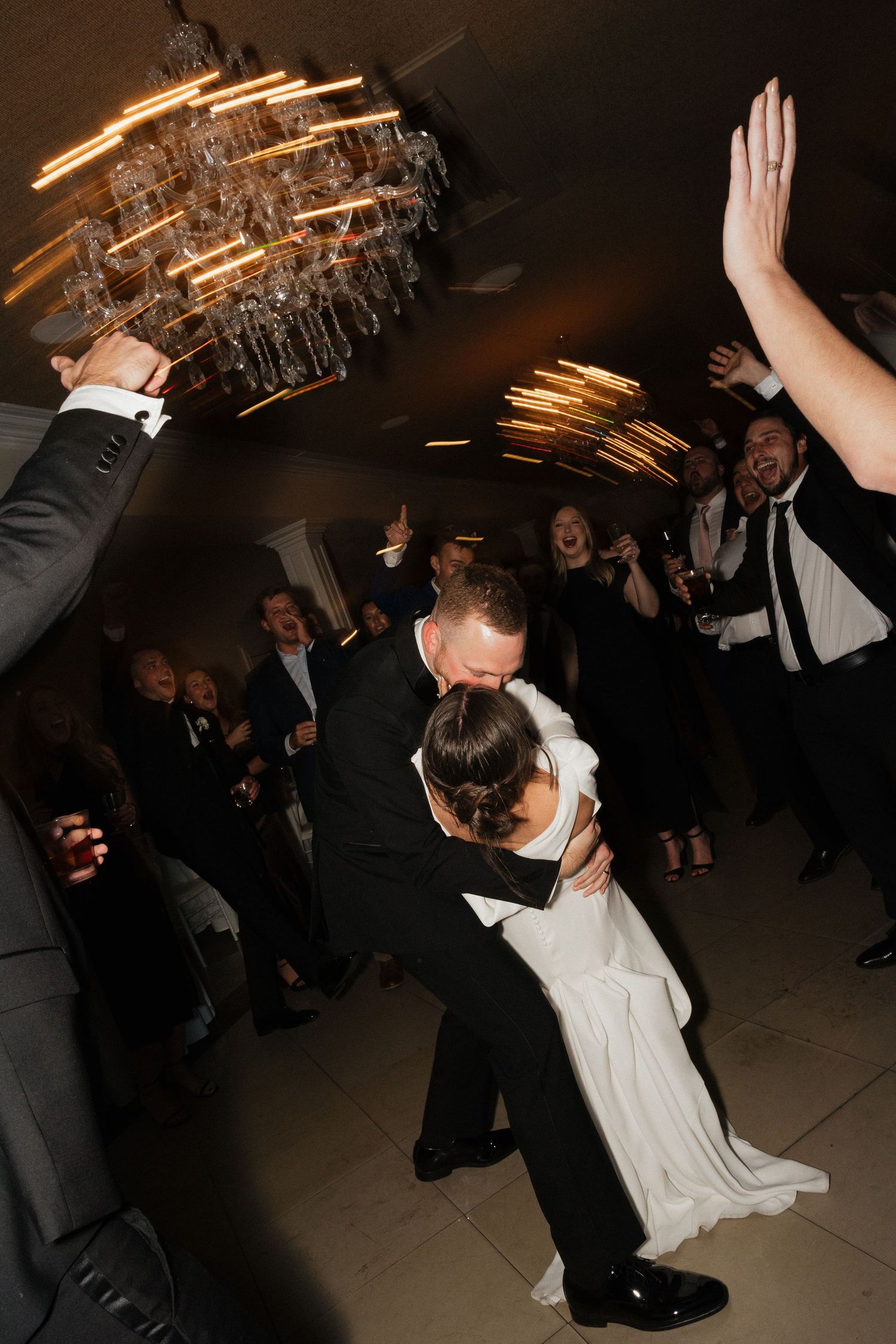 Wedding guests dance and celebrate on the dance floor during a lively reception party.