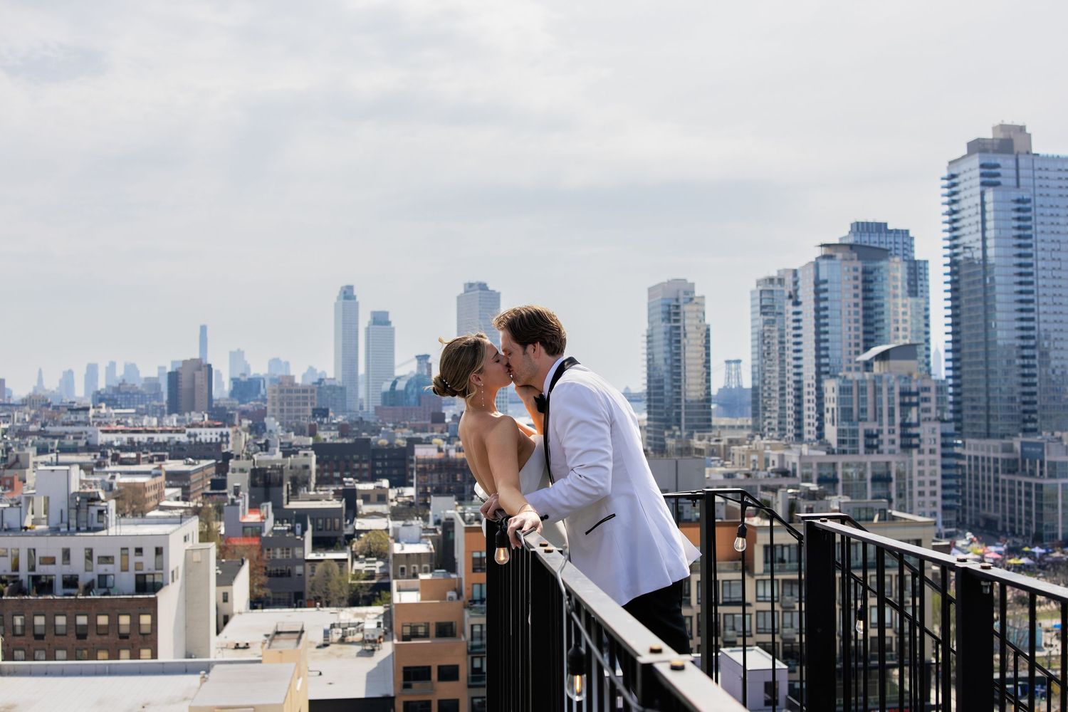 Couple enjoys romantic moment on urban rooftop terrace with panoramic city skyline views of high-rise buildings.