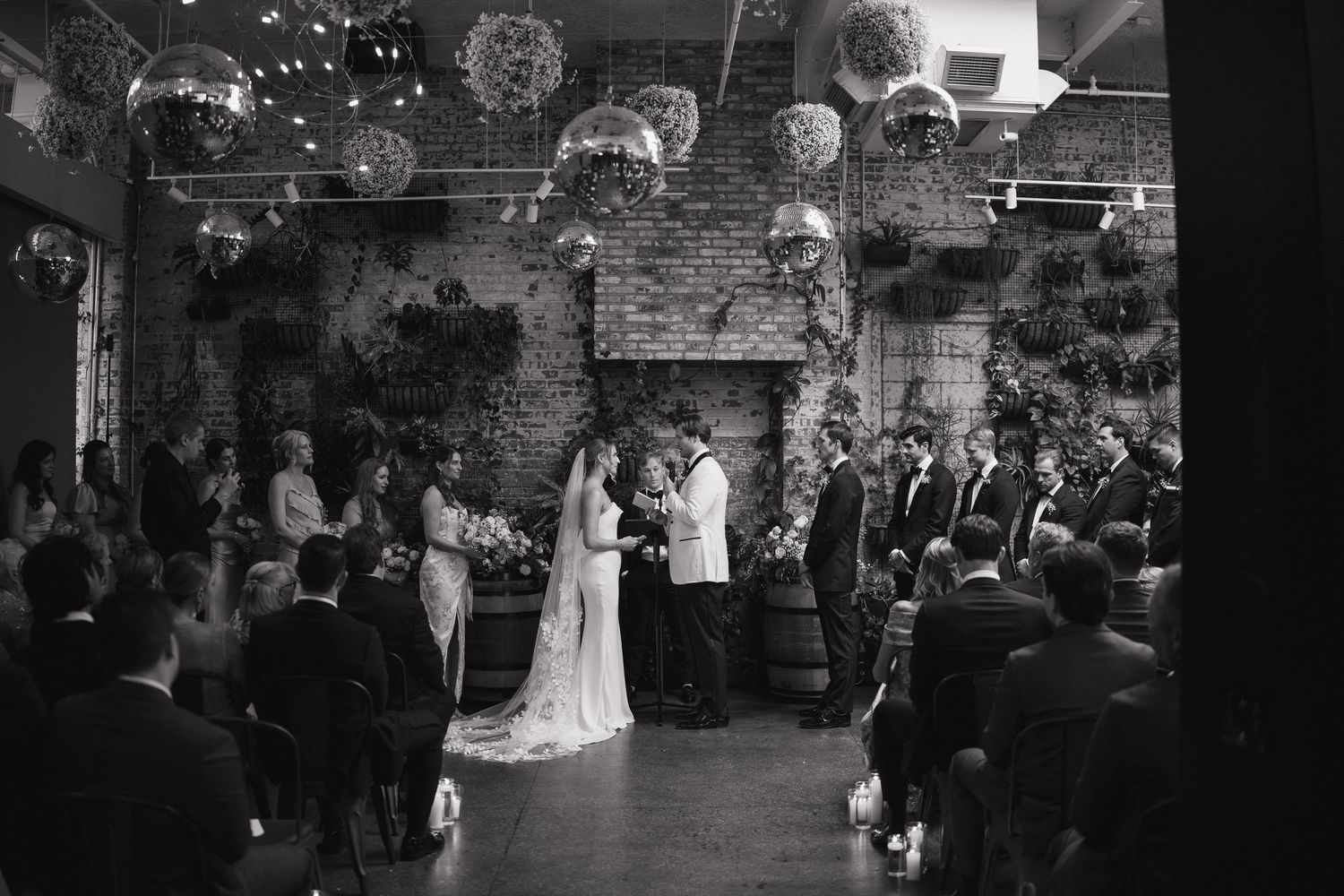 A wedding reception venue with disco balls and string lights creates a dramatic dance floor atmosphere.