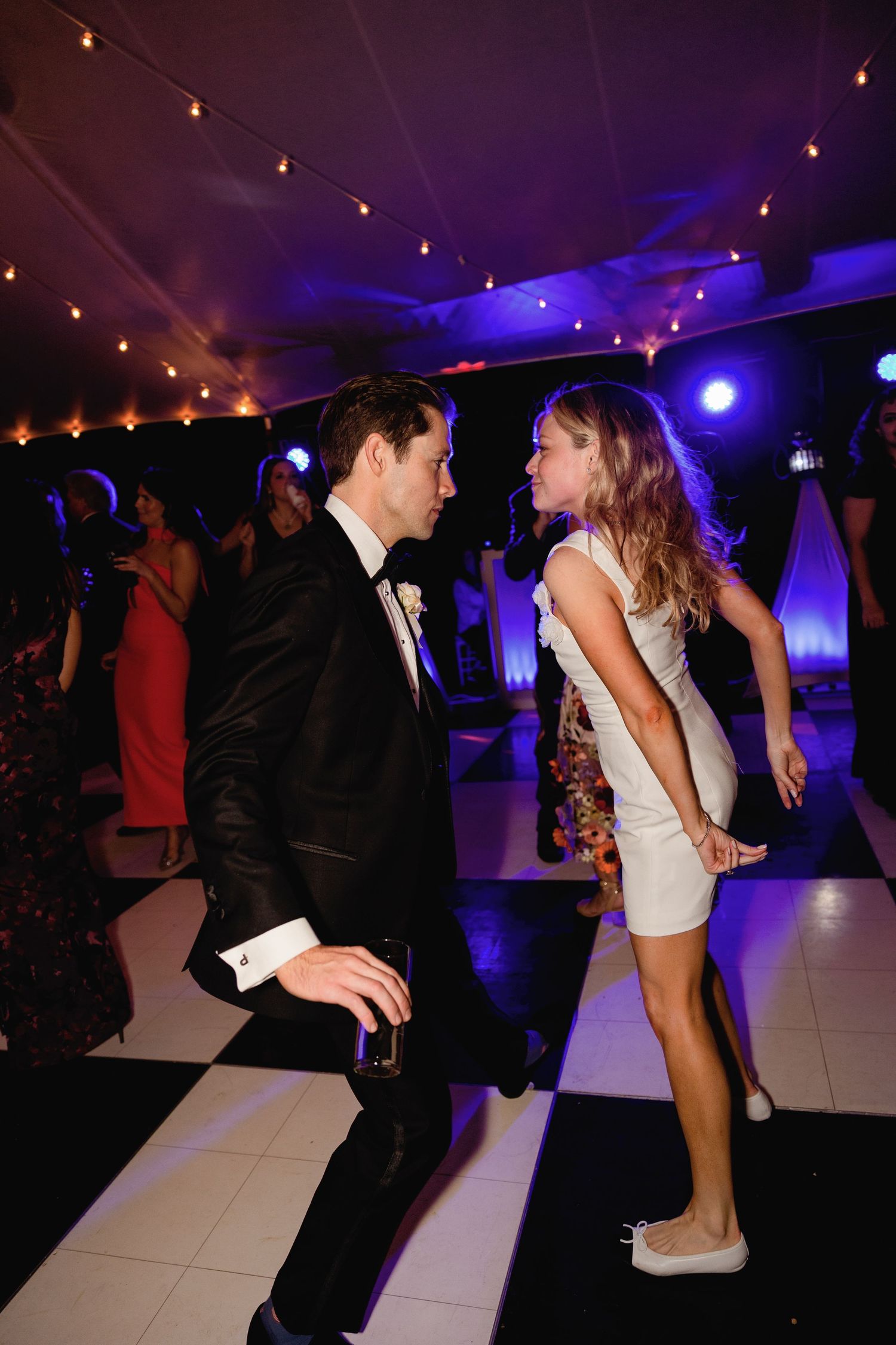 Wedding reception dance floor with blue lighting and string lights creating a festive atmosphere.