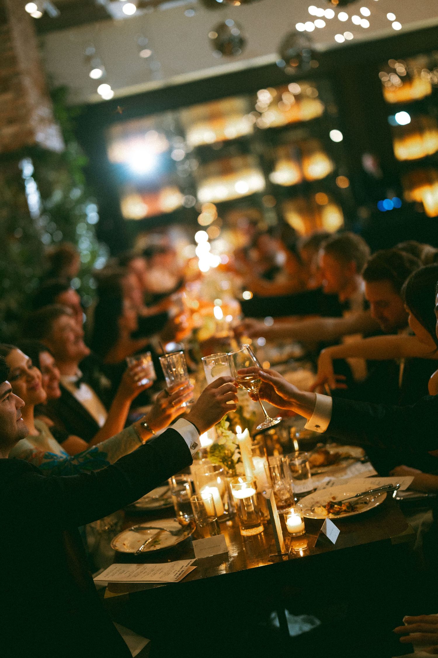 Candlelit wedding reception tables with glowing ambiance in a dimly lit restaurant setting.
