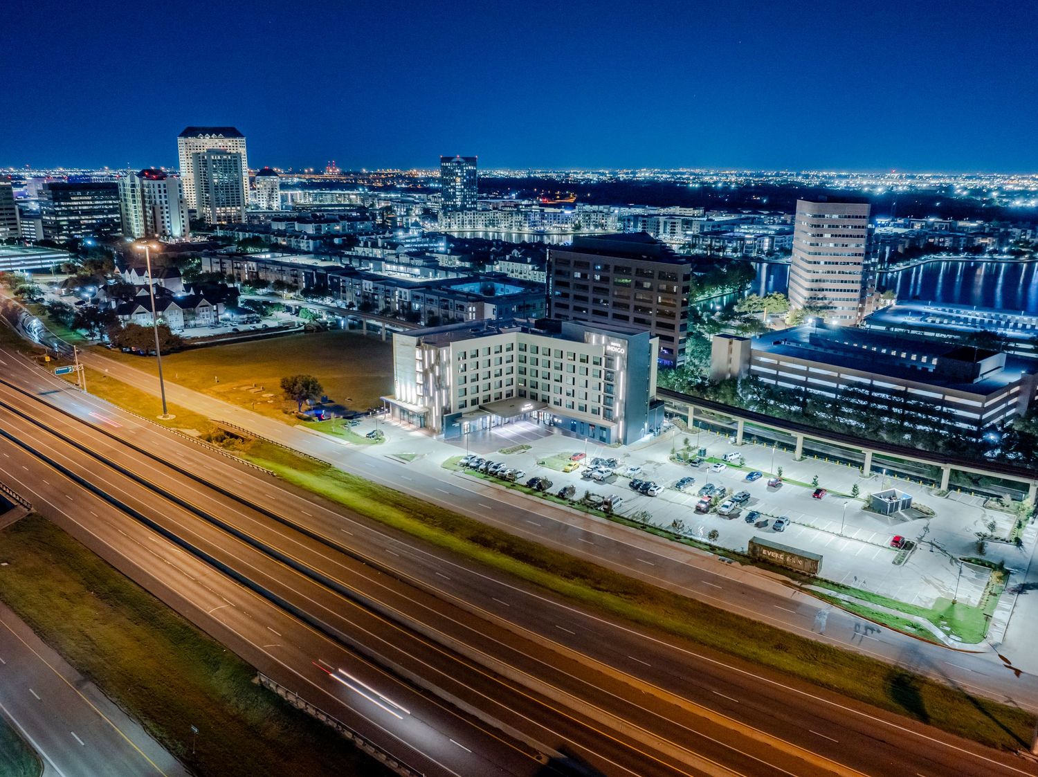 Aerial night view of illuminated city buildings along railroad tracks in downtown Jacksonville, Florida.