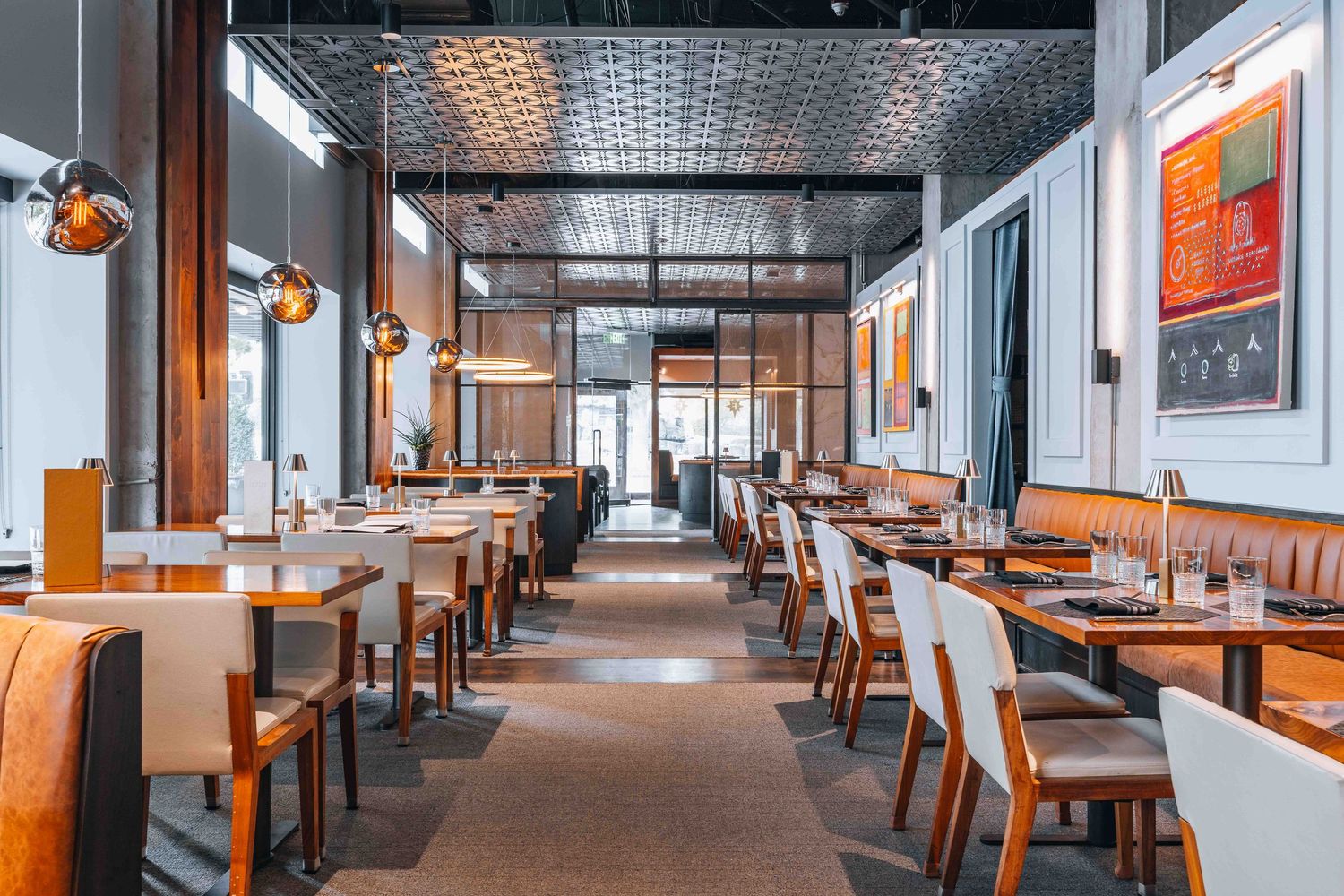 Modern restaurant interior with wooden tables and industrial lighting fixtures creating warm ambiance.