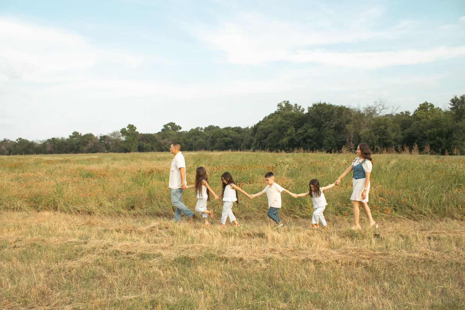family walking in a field holding hands