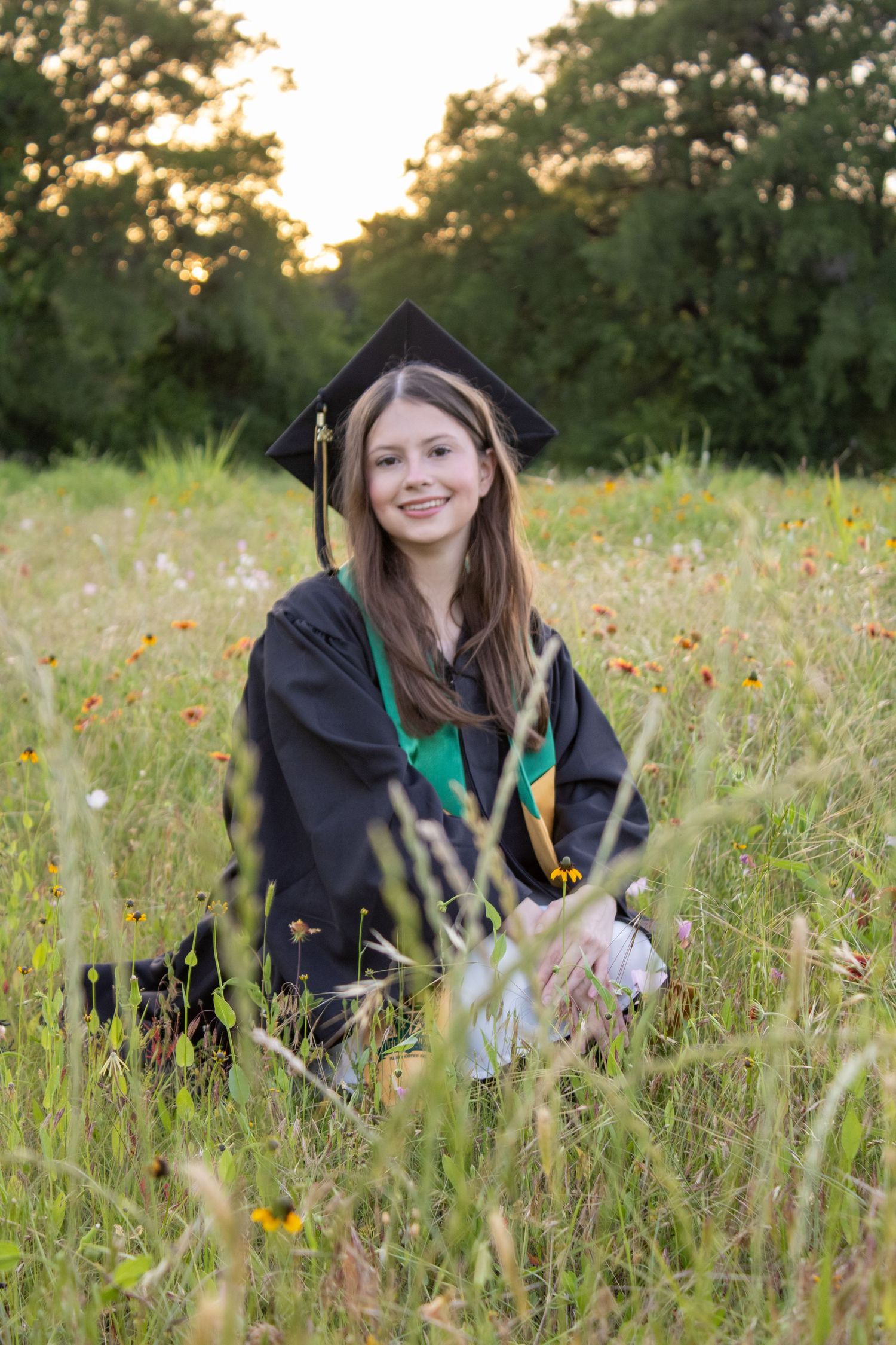 female grad sitting in grass