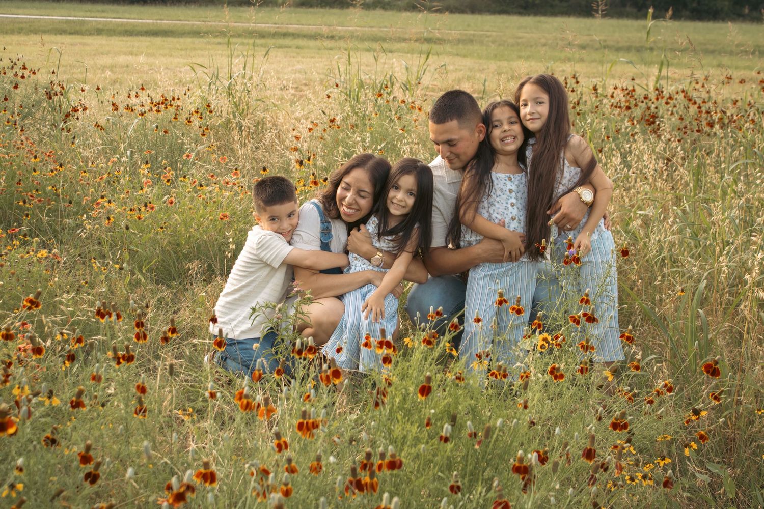 family hugging in wildflower field