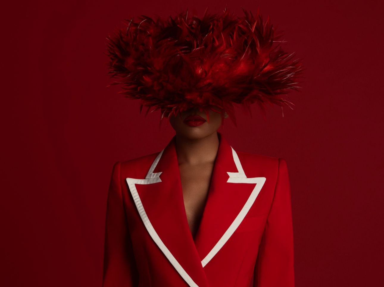 Striking fashion photo with red blazer and dramatic floral headpiece against burgundy background.