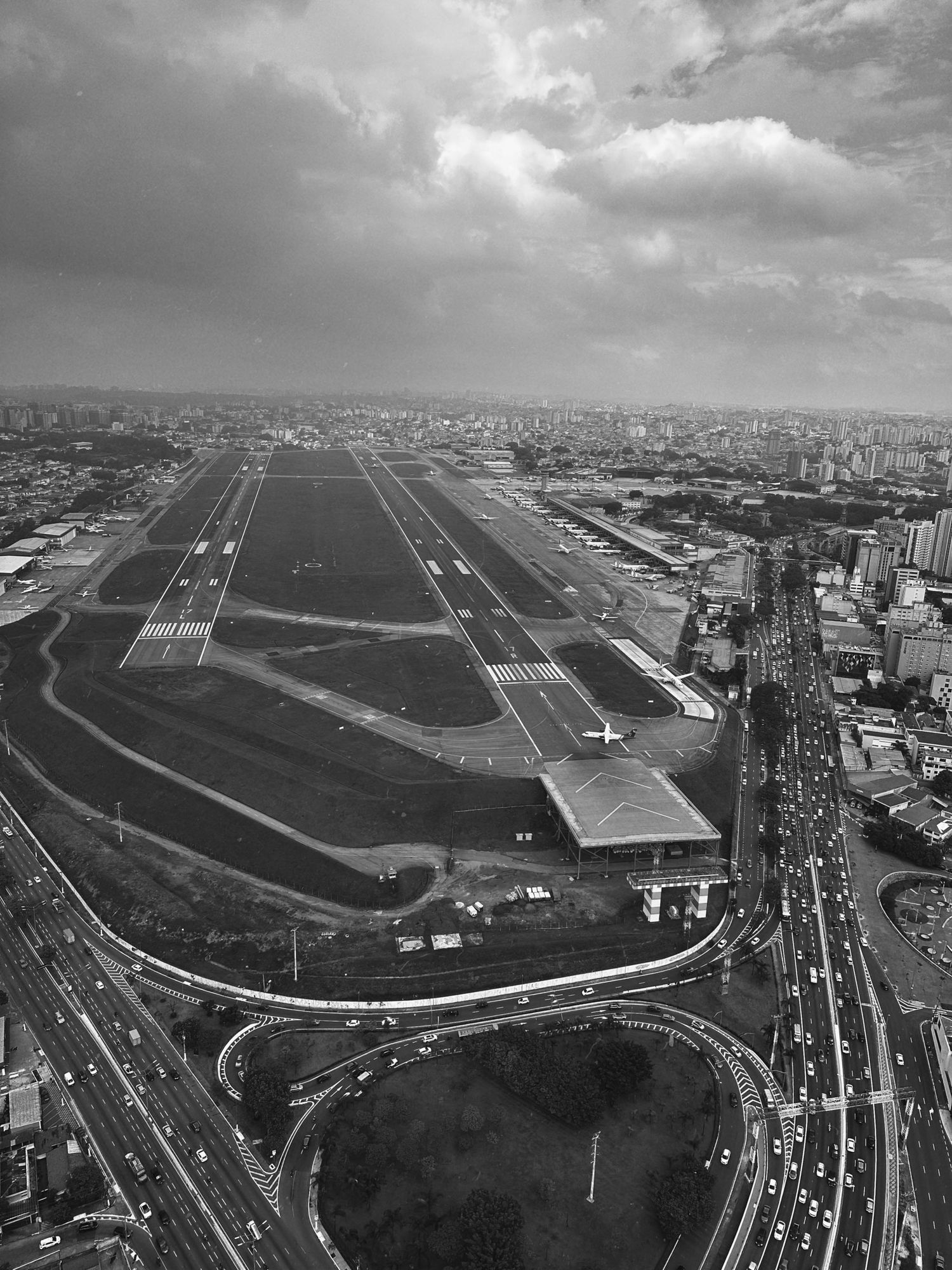 Aerial black and white view of Congonhas Airport runway in Sao Paulo with dense urban development surrounding it.