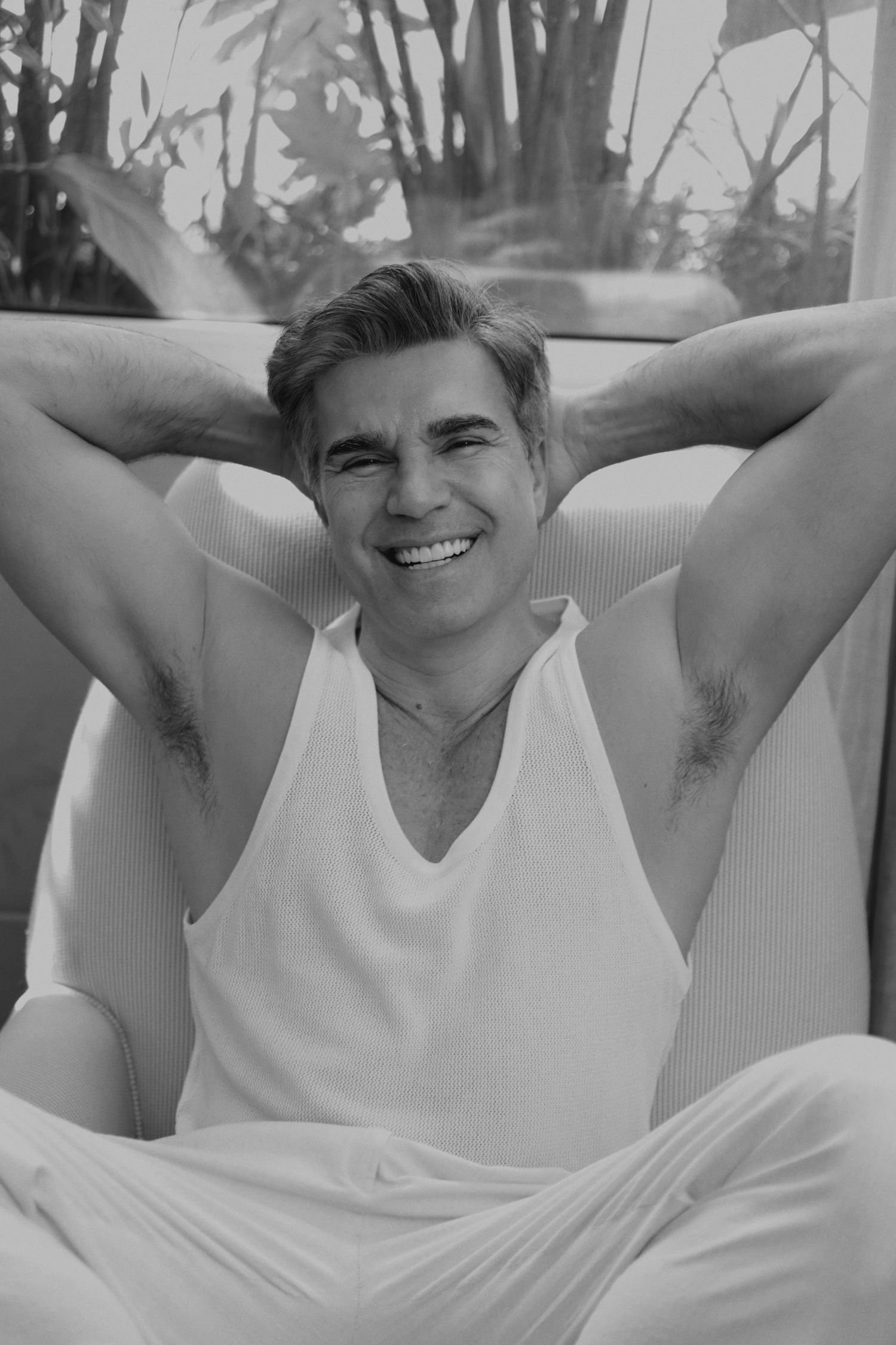 Black and white portrait of person in white tank top relaxing outdoors.