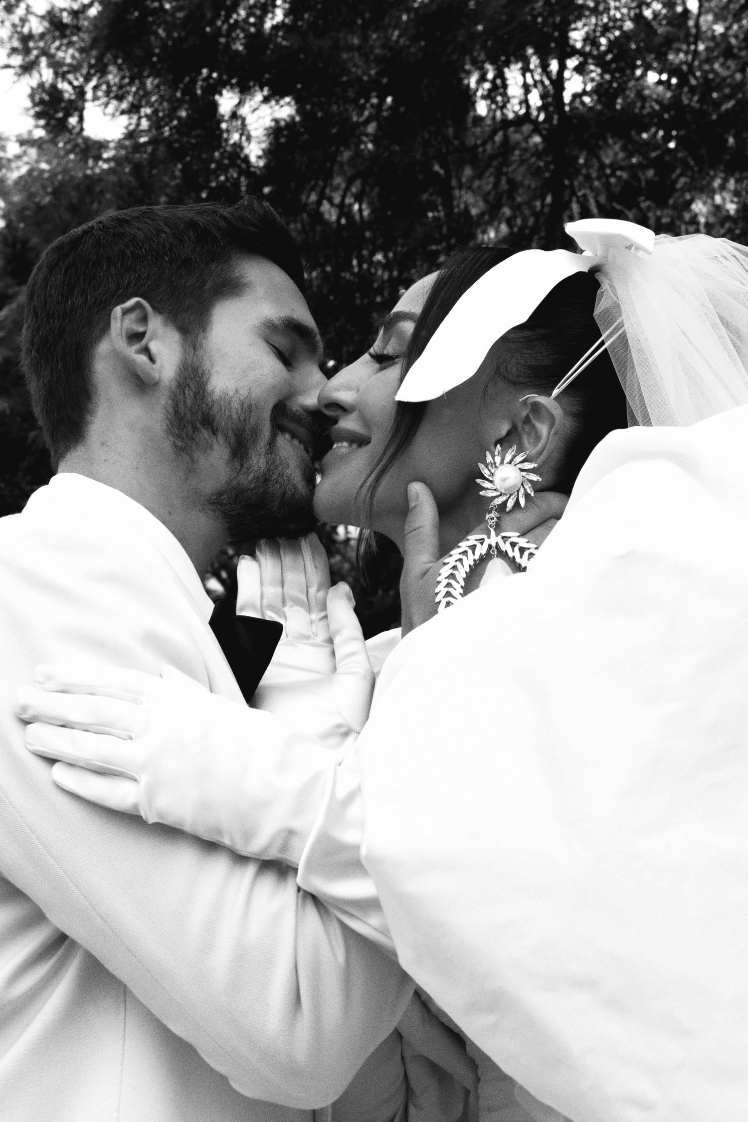 Intimate black and white wedding photo capturing romantic moment between couple in white attire.