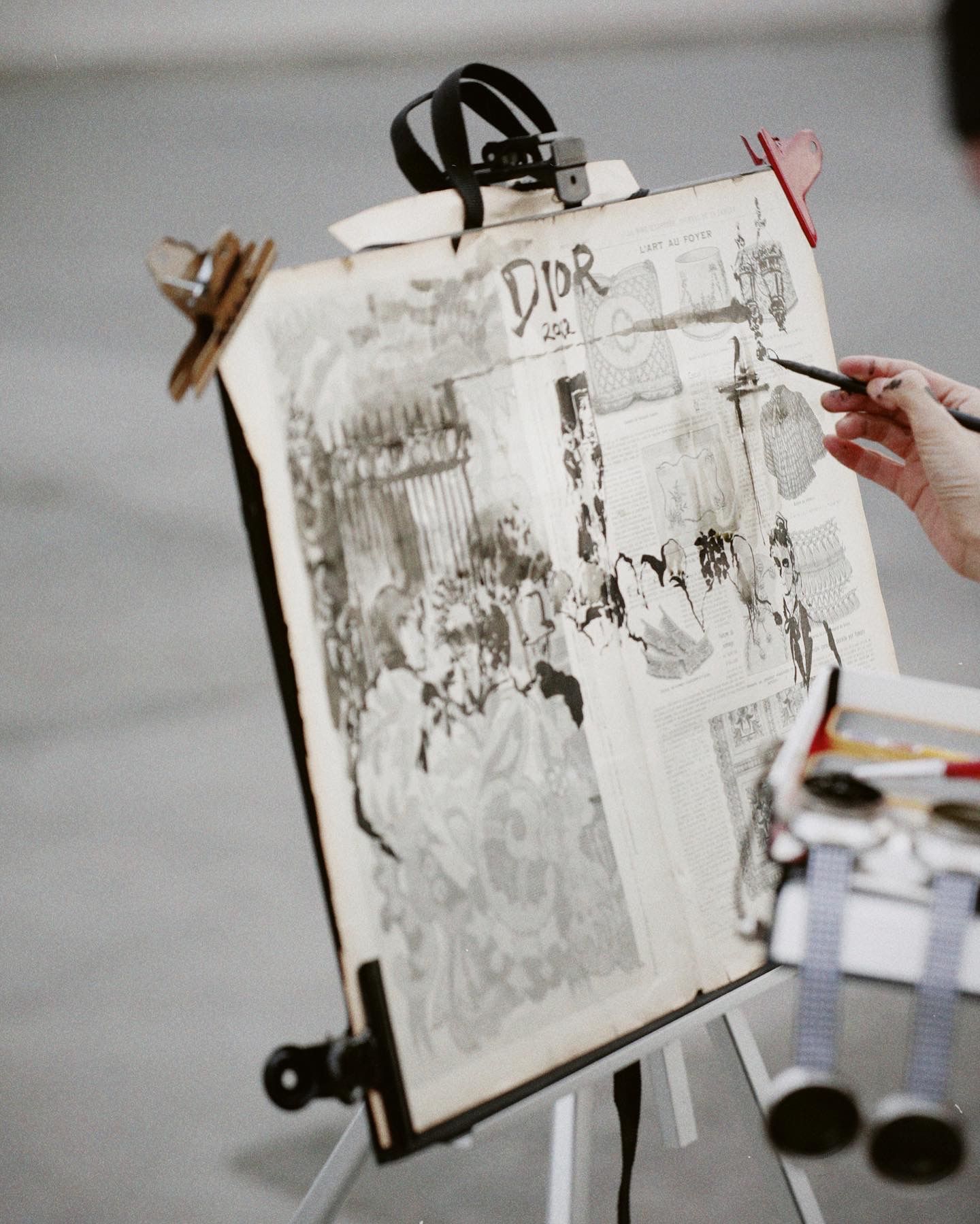 A black and white sketch on an easel shows a street scene being drawn with the text DDR visible at the top.