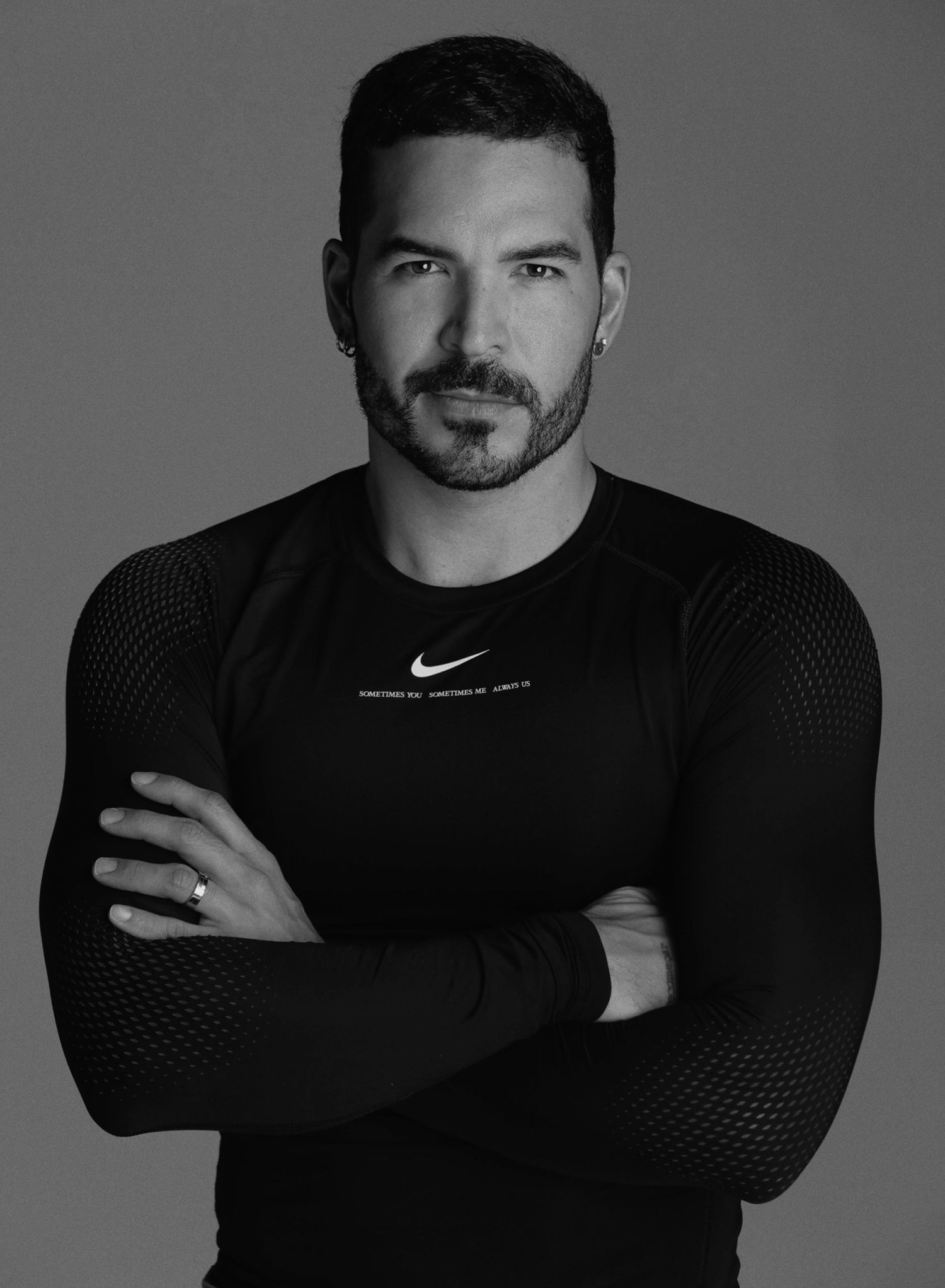 Athletic model in black Nike shirt poses confidently against grey background for dramatic portrait.