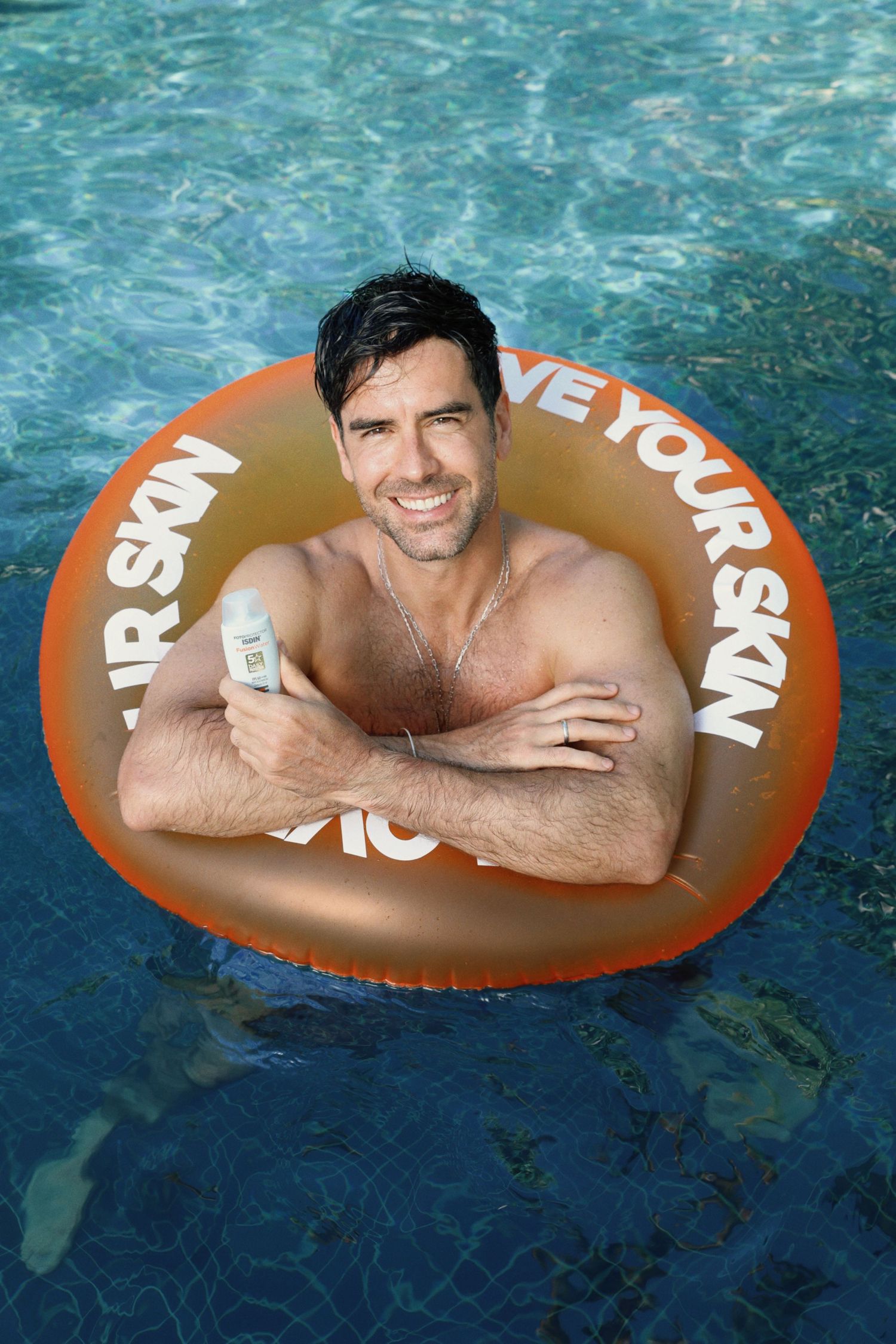 Person lounging in pool with brown inflatable ring displaying text.