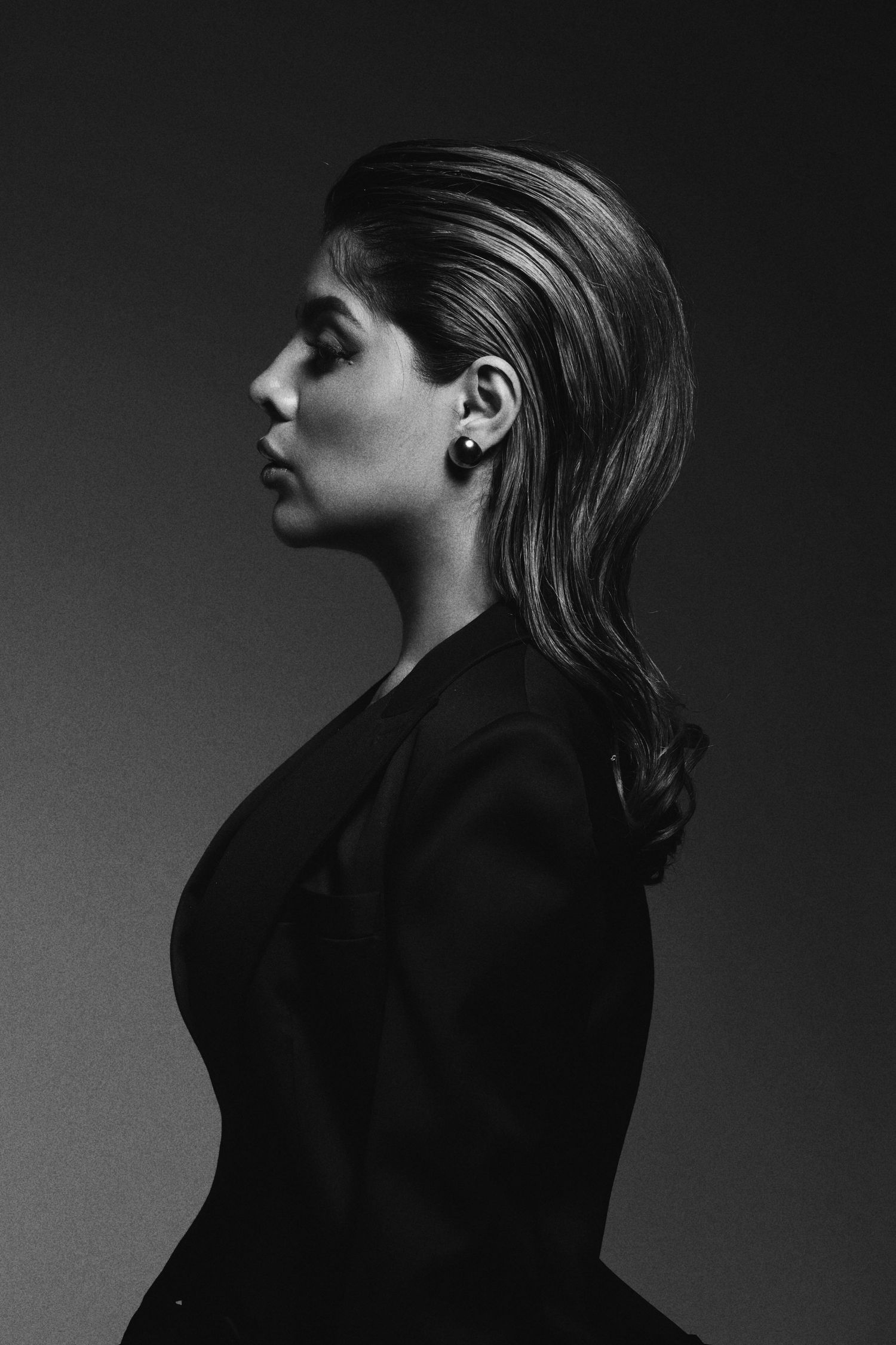 Dramatic black and white profile portrait showing sleek styled hair and elegant posture.