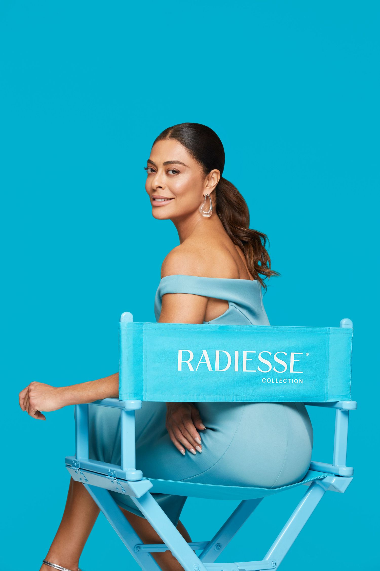 Model poses on blue director's chair with Radiesse branding in matching powder blue dress.
