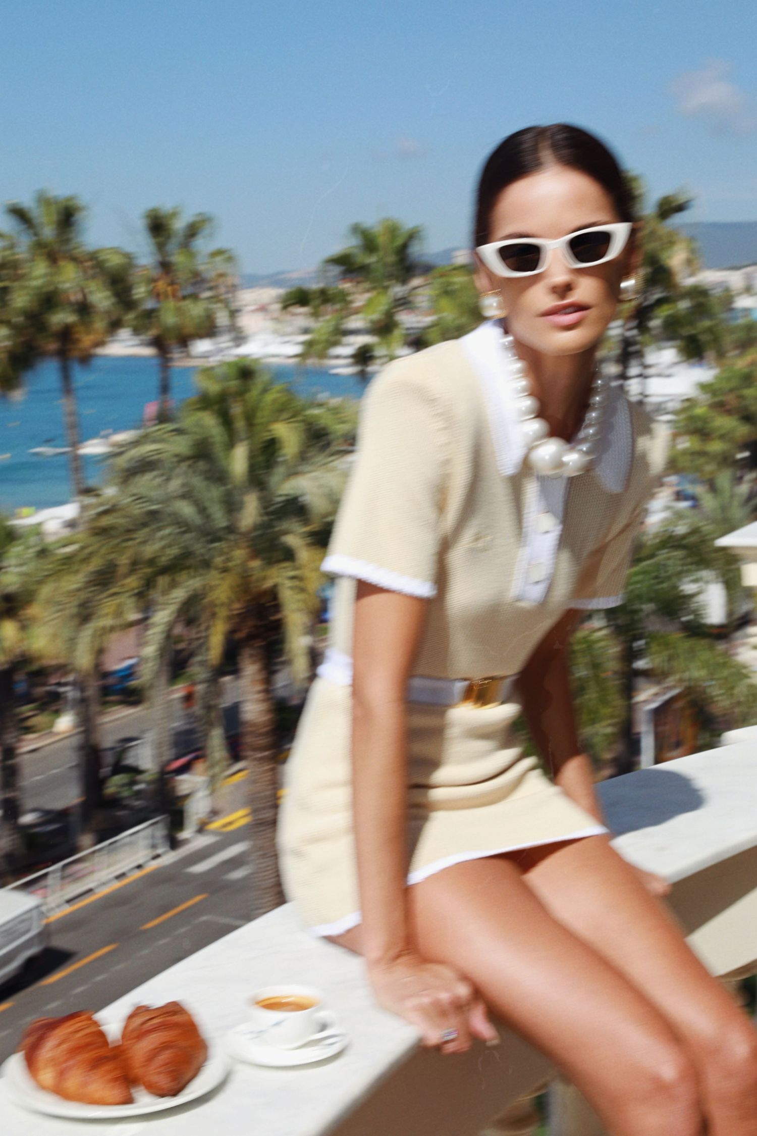 Fashionable scene of breakfast on balcony with coastal views and palm trees.
