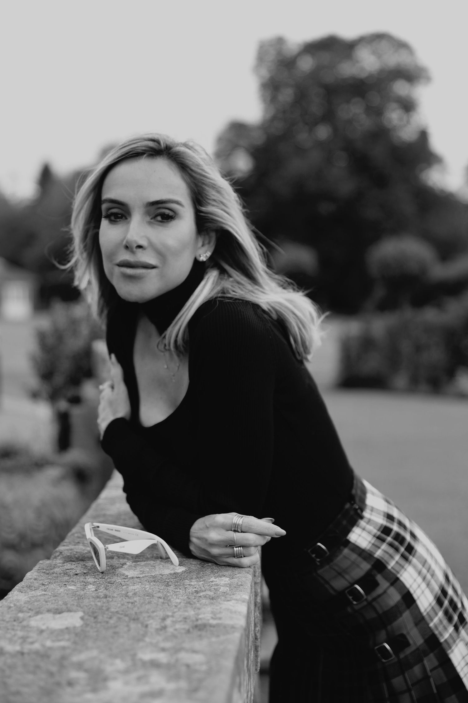 Black and white outdoor portrait with soft natural lighting and plaid skirt detail.