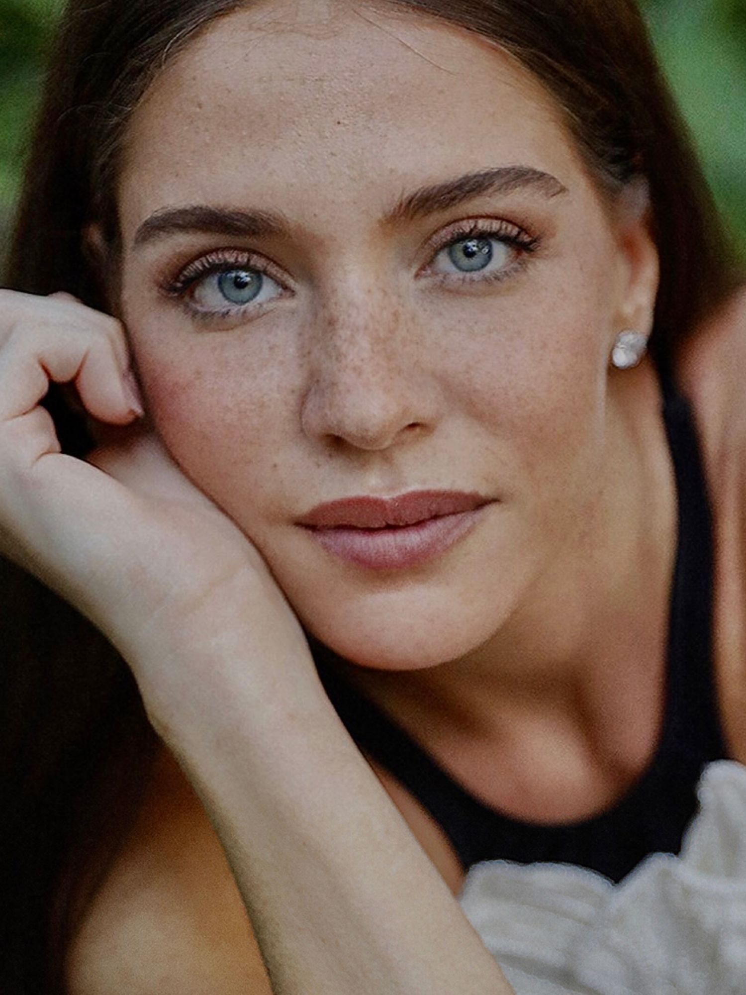 Close-up beauty portrait of a person with striking blue eyes and natural freckles.