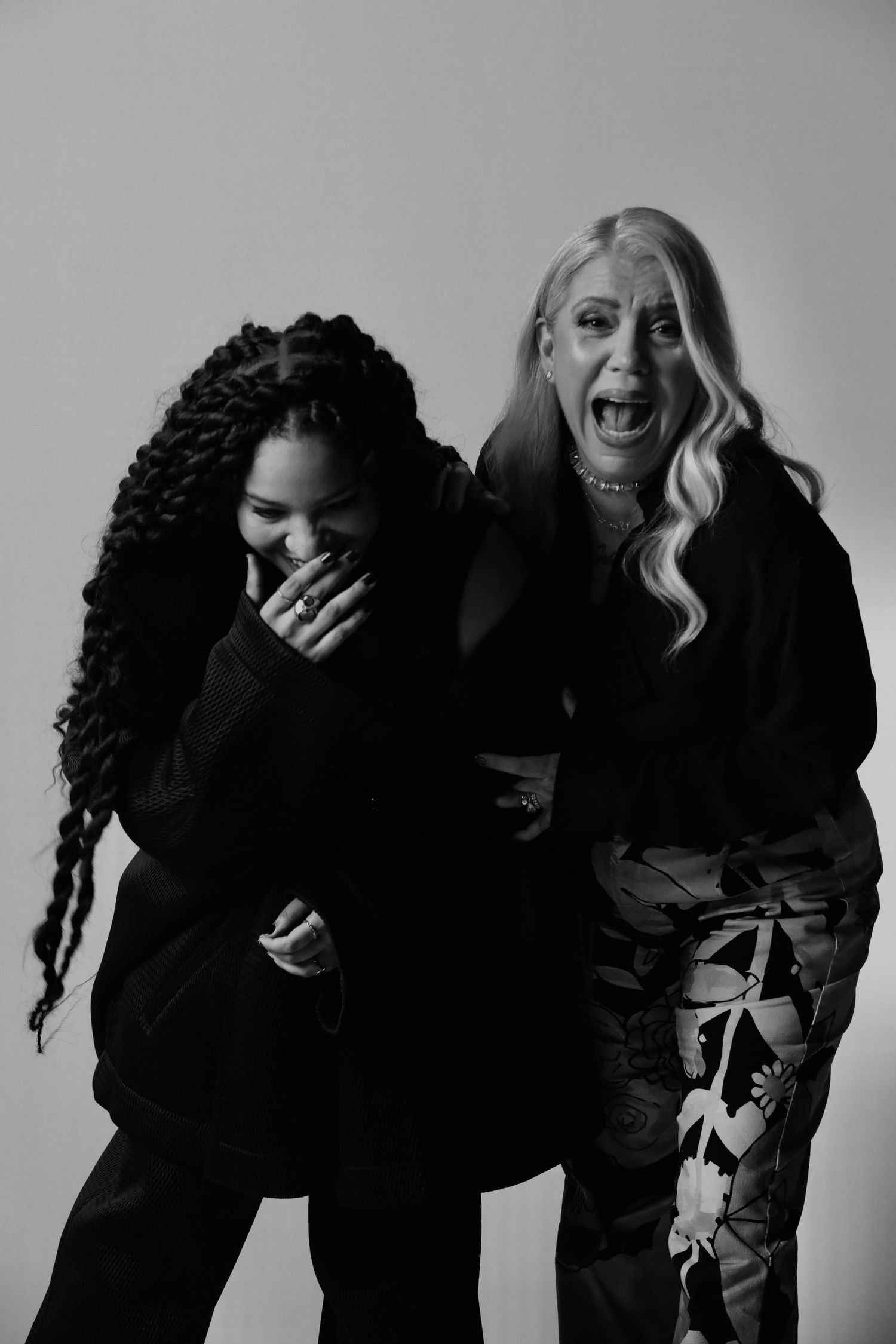 Black and white photo of two people laughing together in dark clothing.