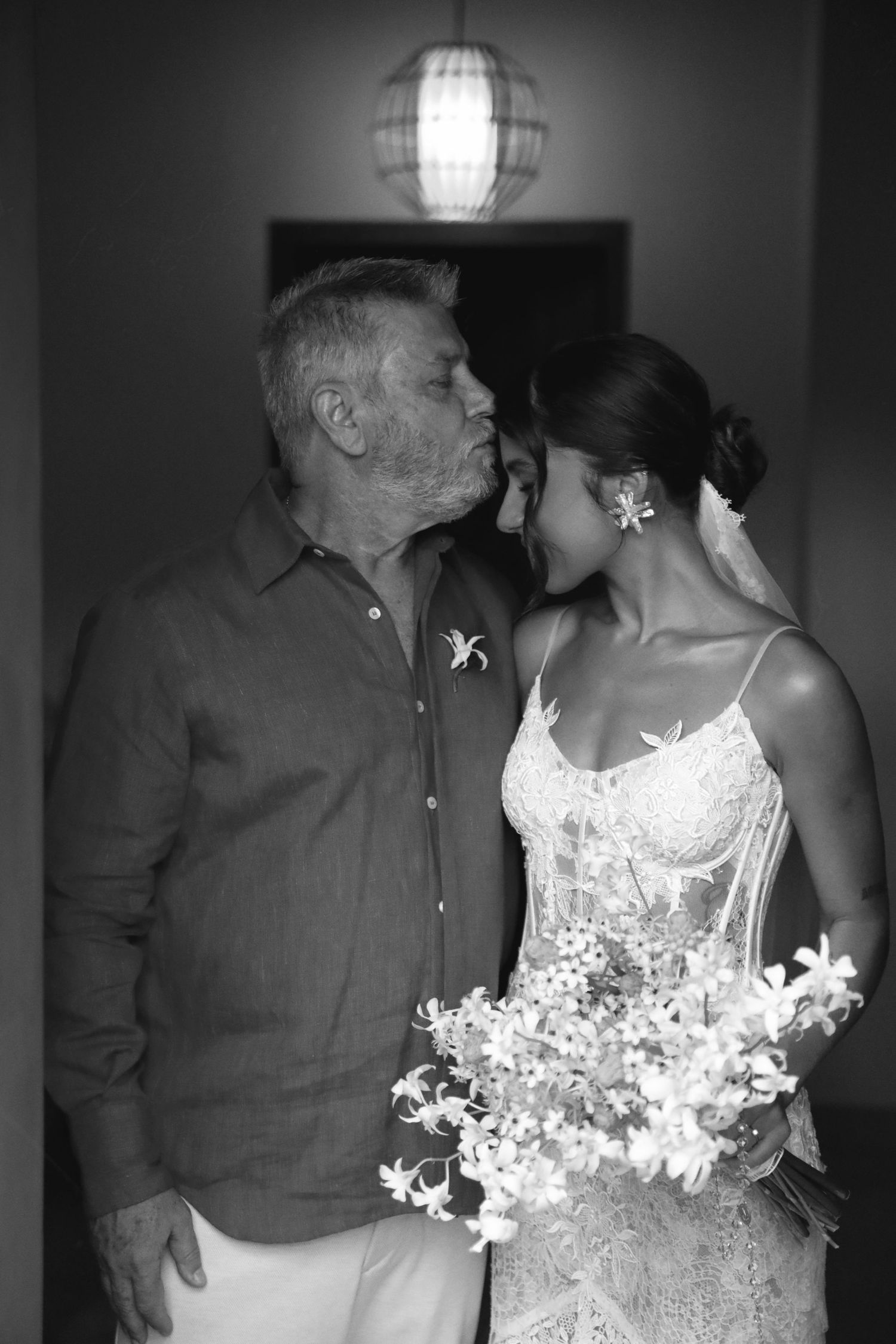 A tender black and white wedding moment showing a sweet whisper, with the bride holding a delicate bouquet of flowers.