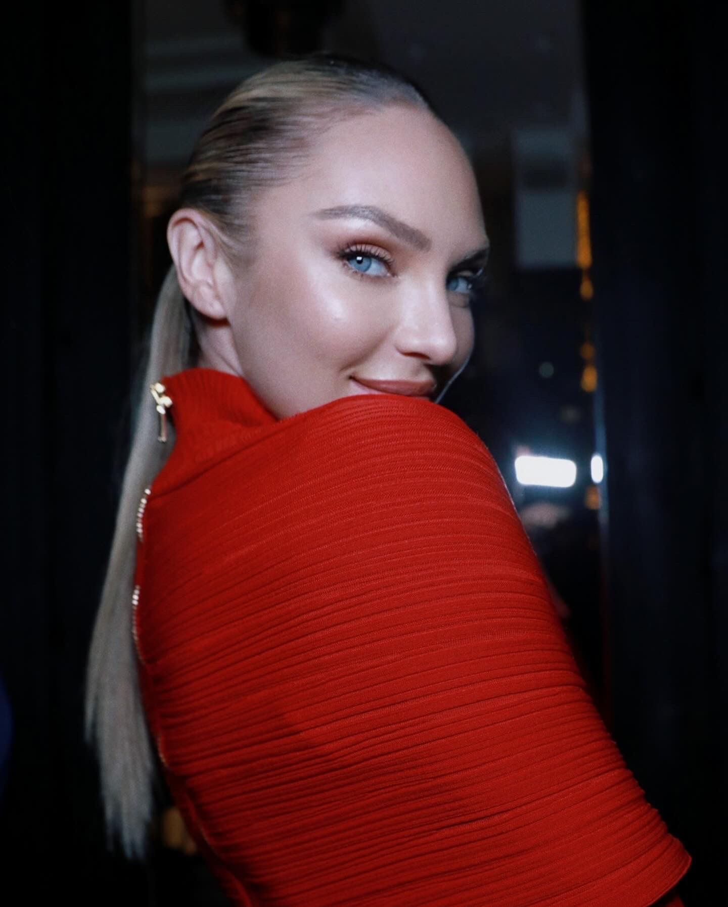 Glamorous fashion portrait in vibrant red dress with sleek pulled-back blonde hair.