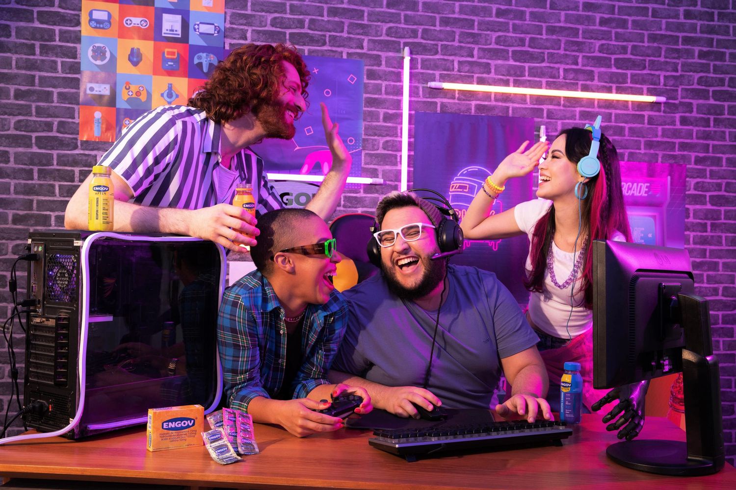 Friends gathered around gaming setup with purple neon lighting and brick wall background.