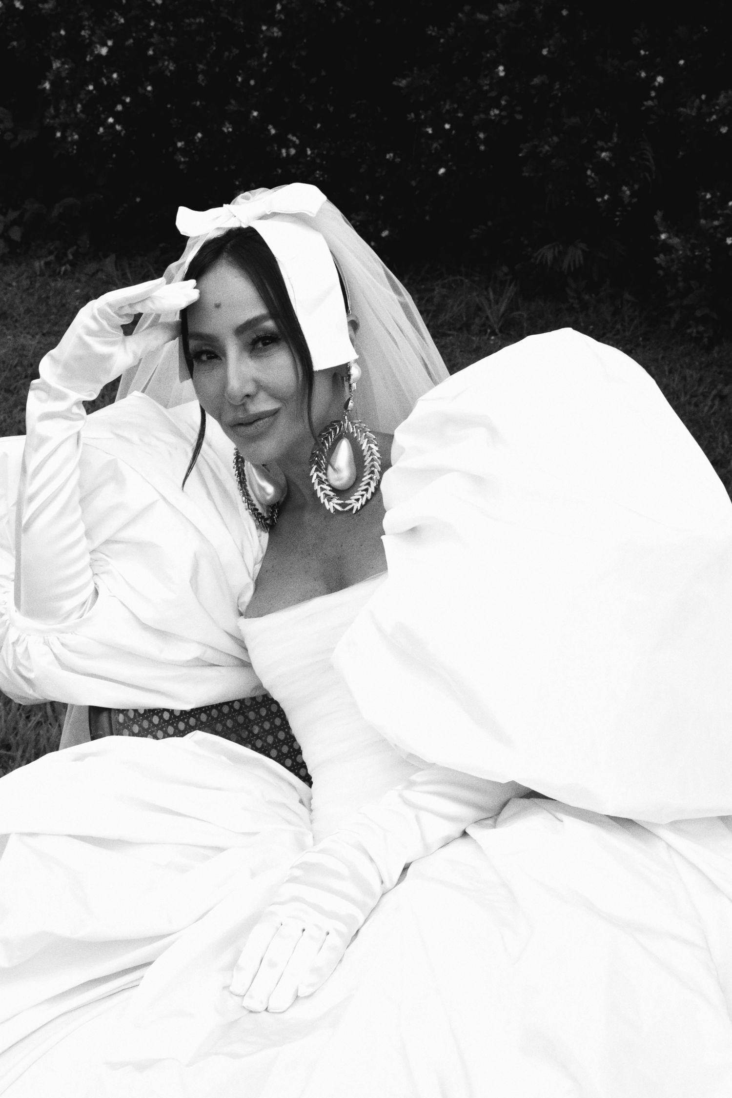 Black and white bridal portrait showing elegant headpiece and statement jewelry details.